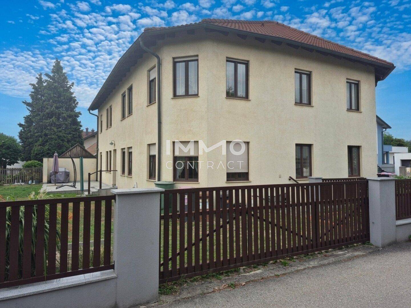Das Haus präsentiert sich von der Straße mit einem stabilen Zaun und einem sonnigen Gartenbereich im Hintergrund.