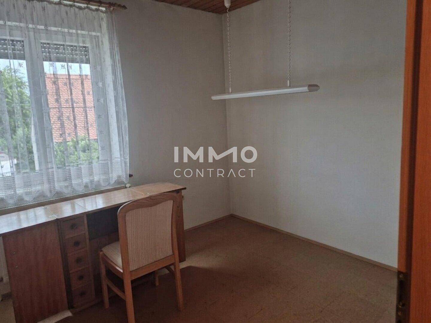 Kleines Arbeitszimmer mit Schreibtisch, Laminatboden und Fenster mit Blick nach draußen.