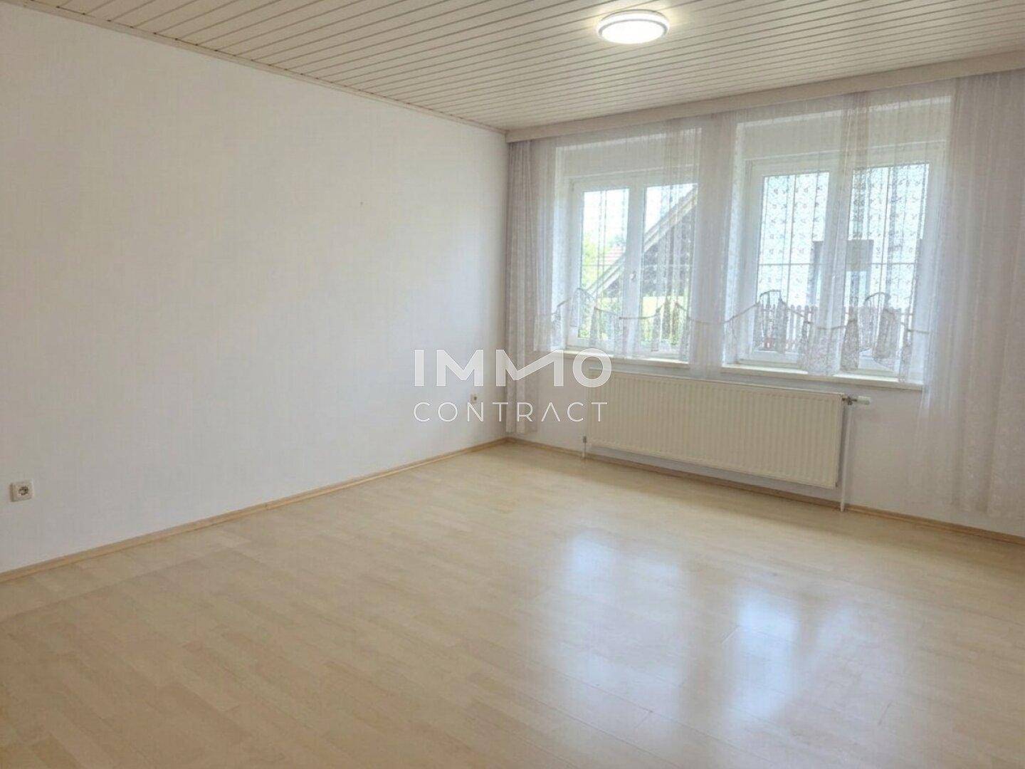Heller Wohnraum mit Laminatboden, Holzdecke und großen Fenstern für viel Tageslicht.