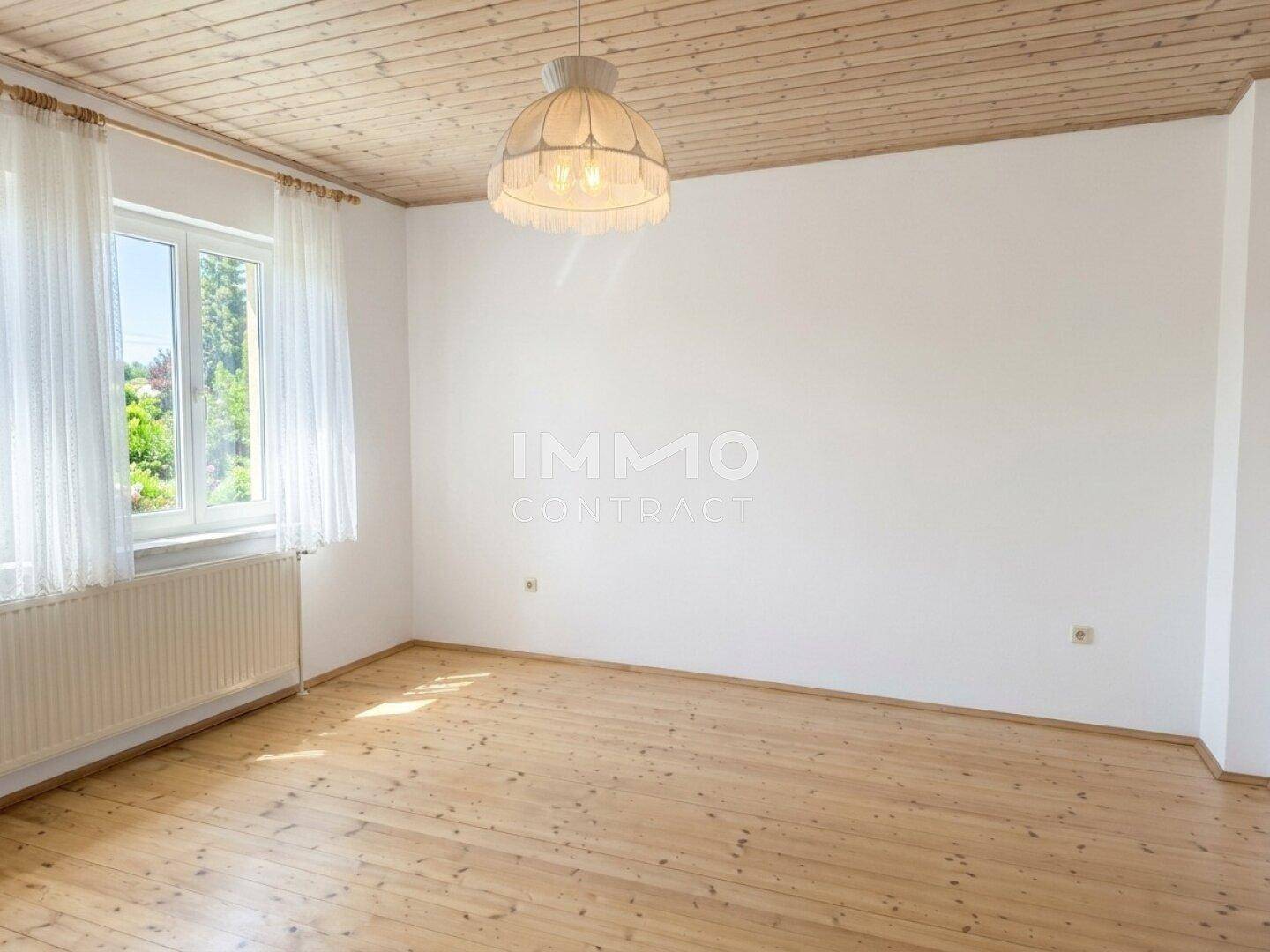 Helles Schlafzimmer mit Holzdielenboden, Holzdecke und einem großen Fenster.