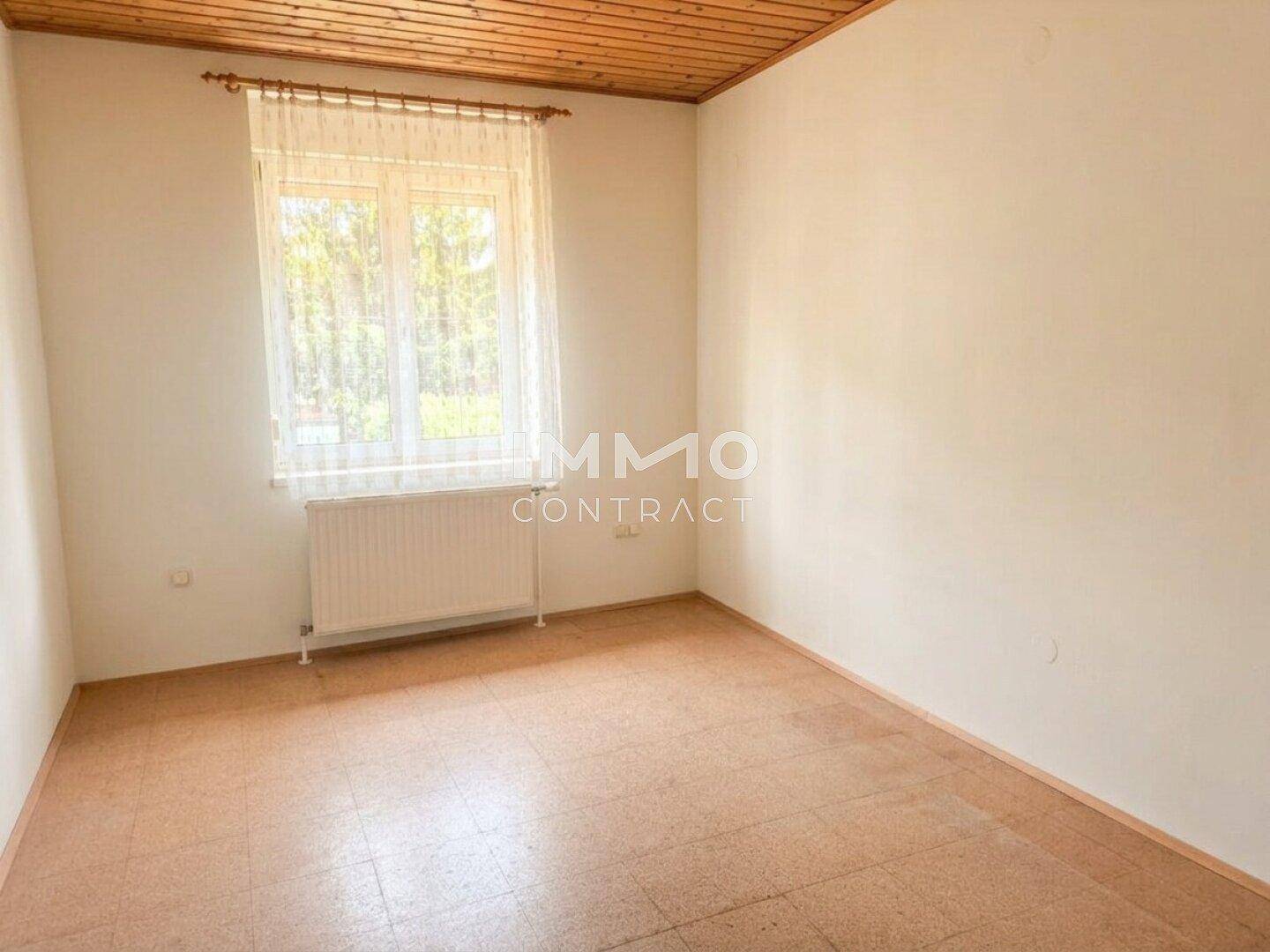 Kleines Zimmer mit Laminatboden, Holzdecke und einem Fenster, ideal als Kinderzimmer.