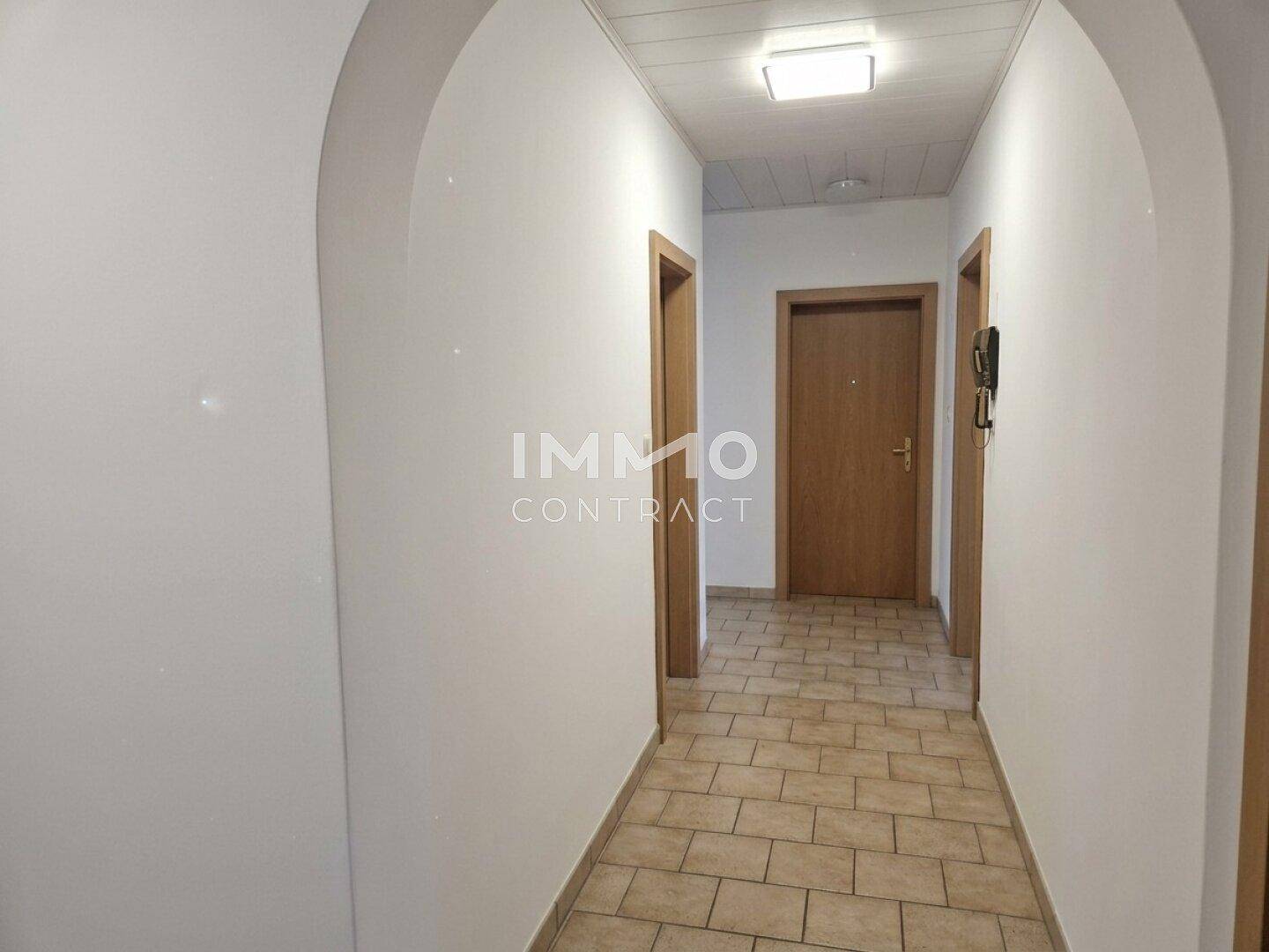 Geräumiger Flur mit Fliesenboden und mehreren Holztüren, die zu den Zimmern führen.
