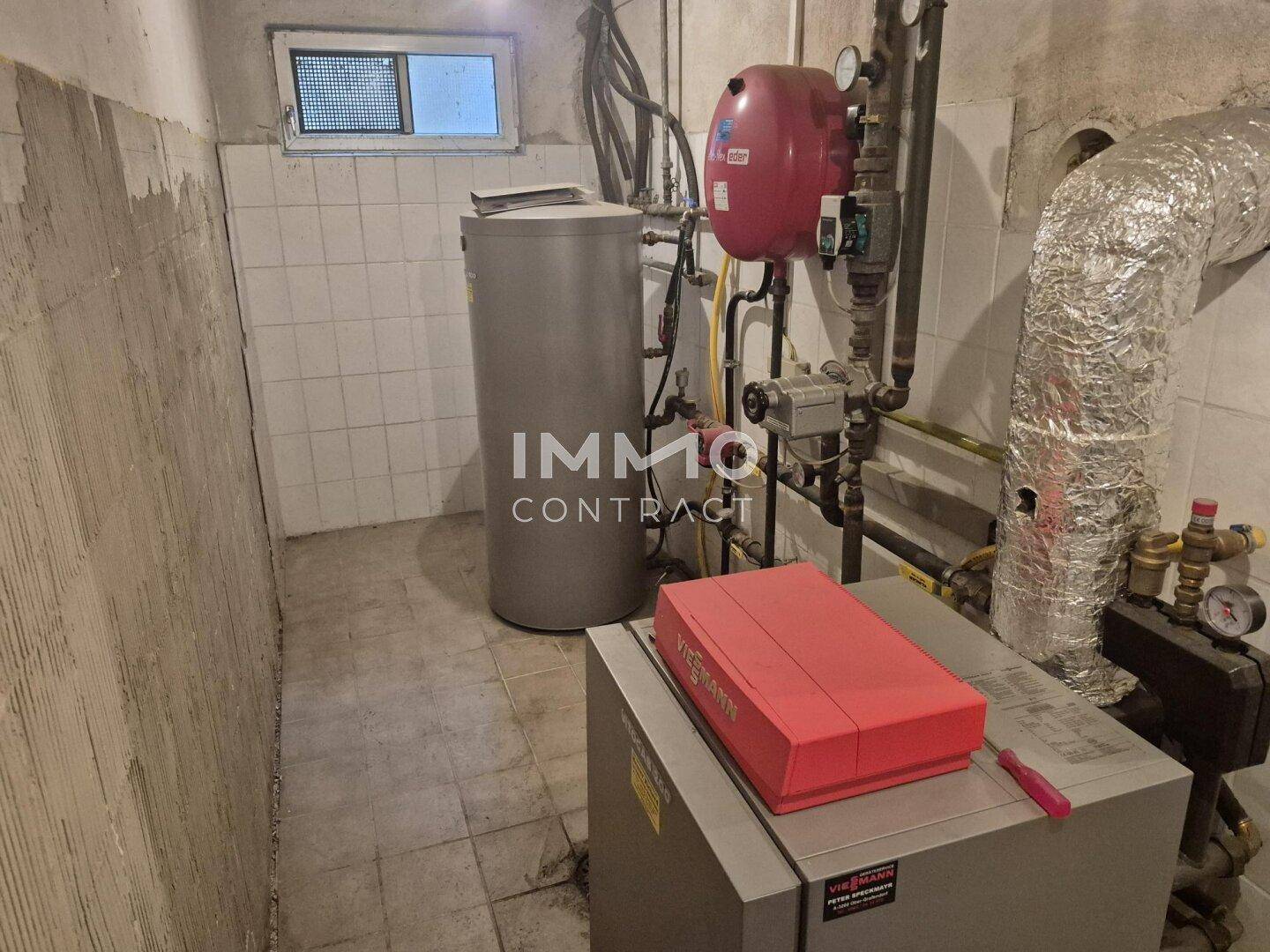 Heizungsraum im Keller mit Warmwasserspeicher und moderner Heizungsanlage.