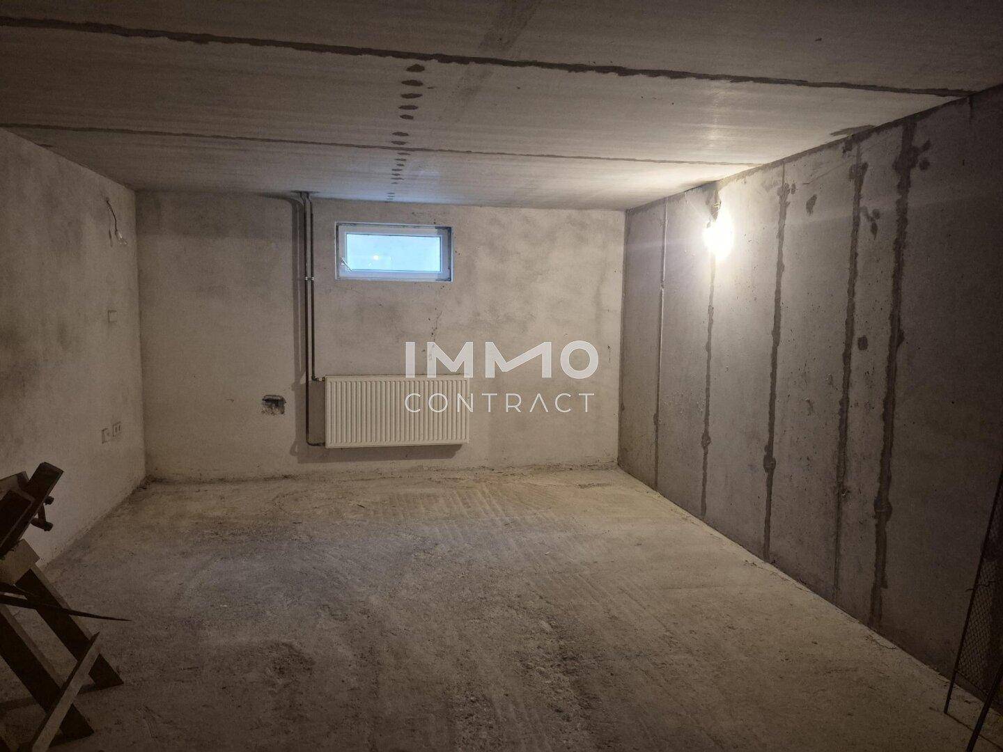 Heller Kellerraum mit Betonwänden, Betonboden und einem kleinen Fenster für Belüftung.