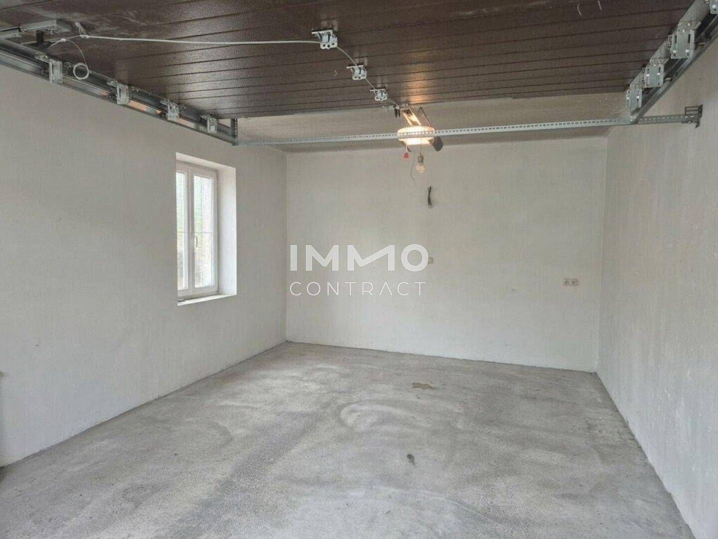 Geräumige Garage mit Betonboden und einem Fenster, bietet Platz für ein Fahrzeug.
