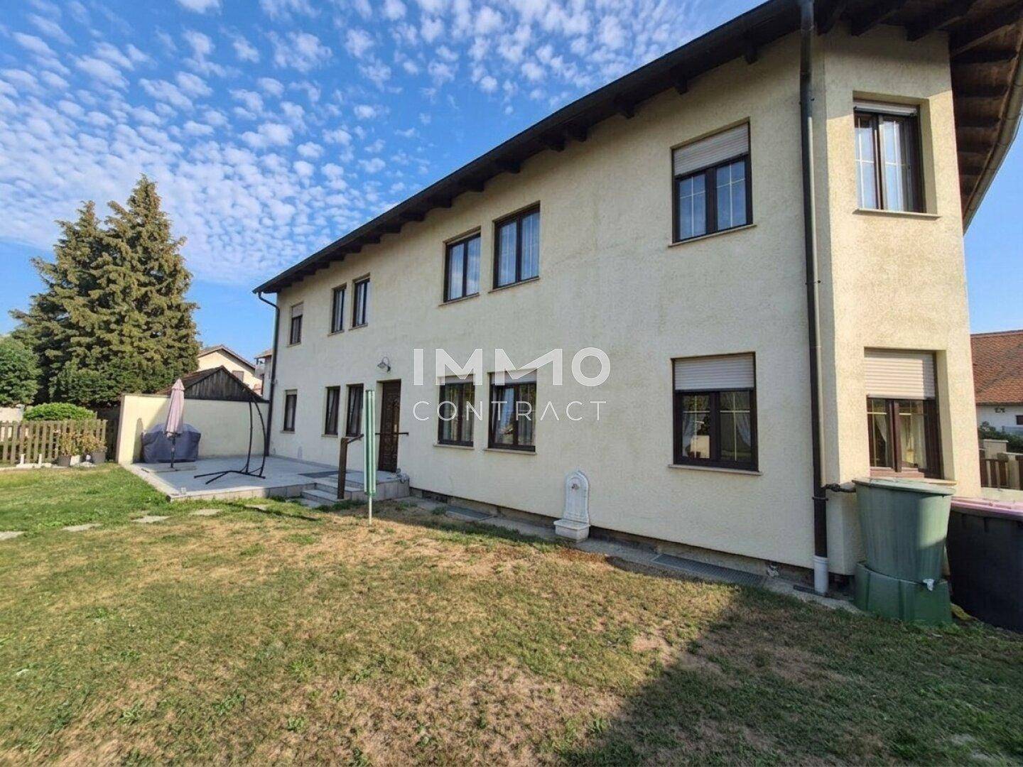 Rückansicht des Hauses mit großem Rasenbereich und einer gemütlichen Terrasse mit Gartenmöbeln.