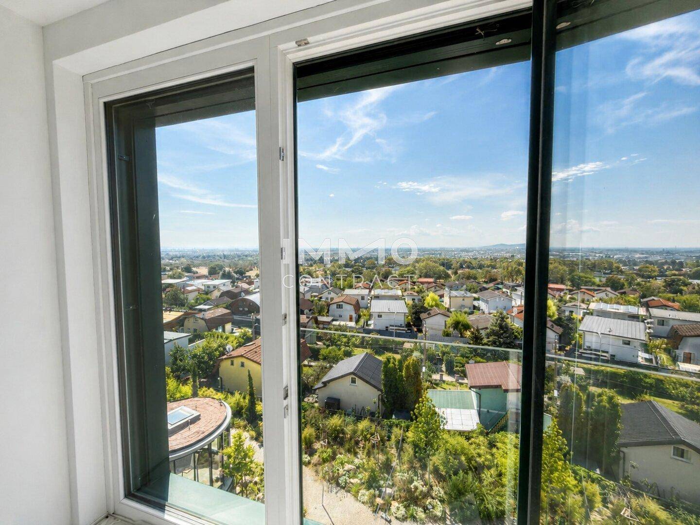 Heller Innenraum mit großem Fenster und weitem Blick über die umliegende Wohnsiedlung.