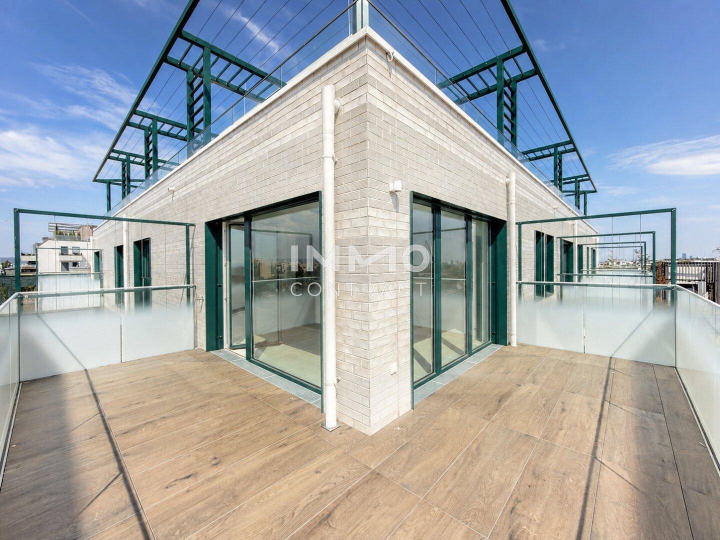 Große Dachterrasse mit Holzboden und moderner Architektur des Gebäudes im Hintergrund.