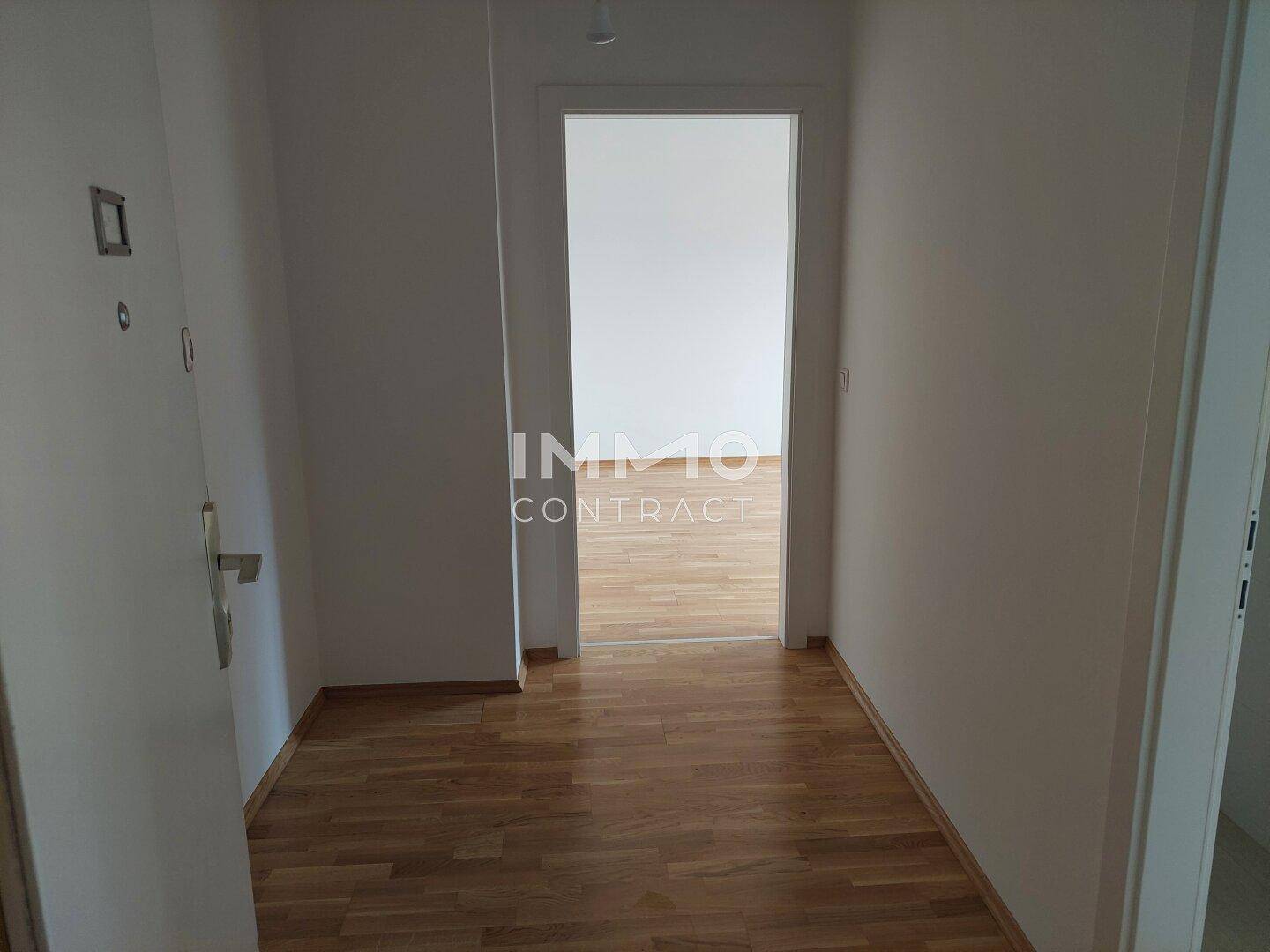 Heller Flur mit Holzboden und Zugang zu weiteren Räumen.