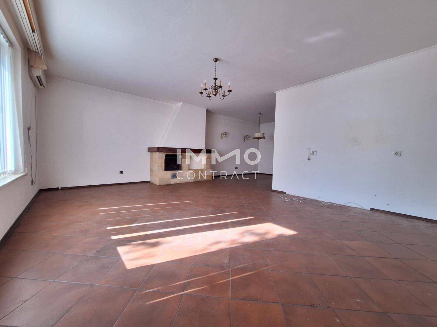 Heller Wohnbereich mit großem Fenster und Kamin, bietet viel Potenzial für individuelle Gestaltung.