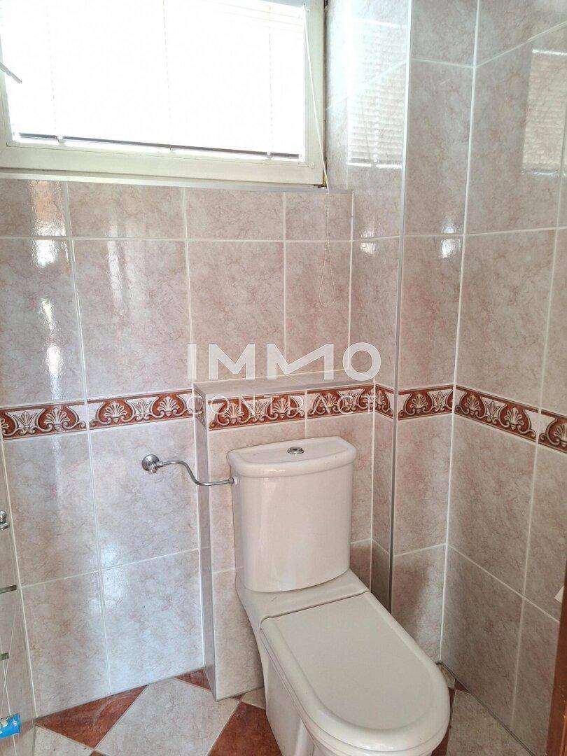 Kleines WC mit Fliesen an Wänden und Boden, ausgestattet mit einem Fenster für Belüftung.
