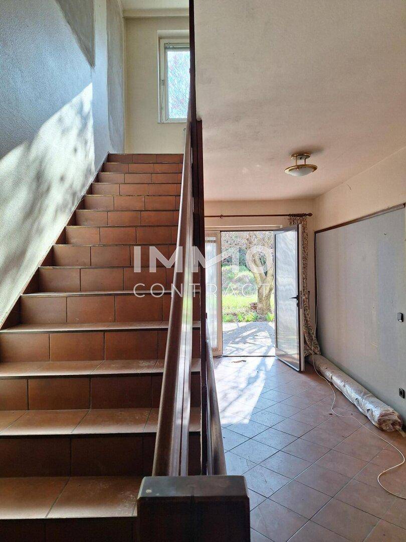 Geräumiger Flur mit gefliester Treppe und Zugang zum Garten, hell und einladend.