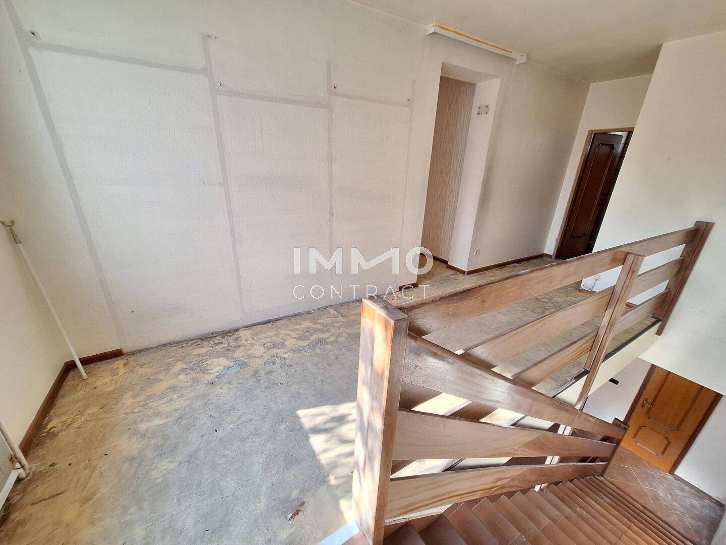 Oberer Flurbereich mit Holzgeländer und vorbereiteten Wänden, ideal für Renovierungsarbeiten.