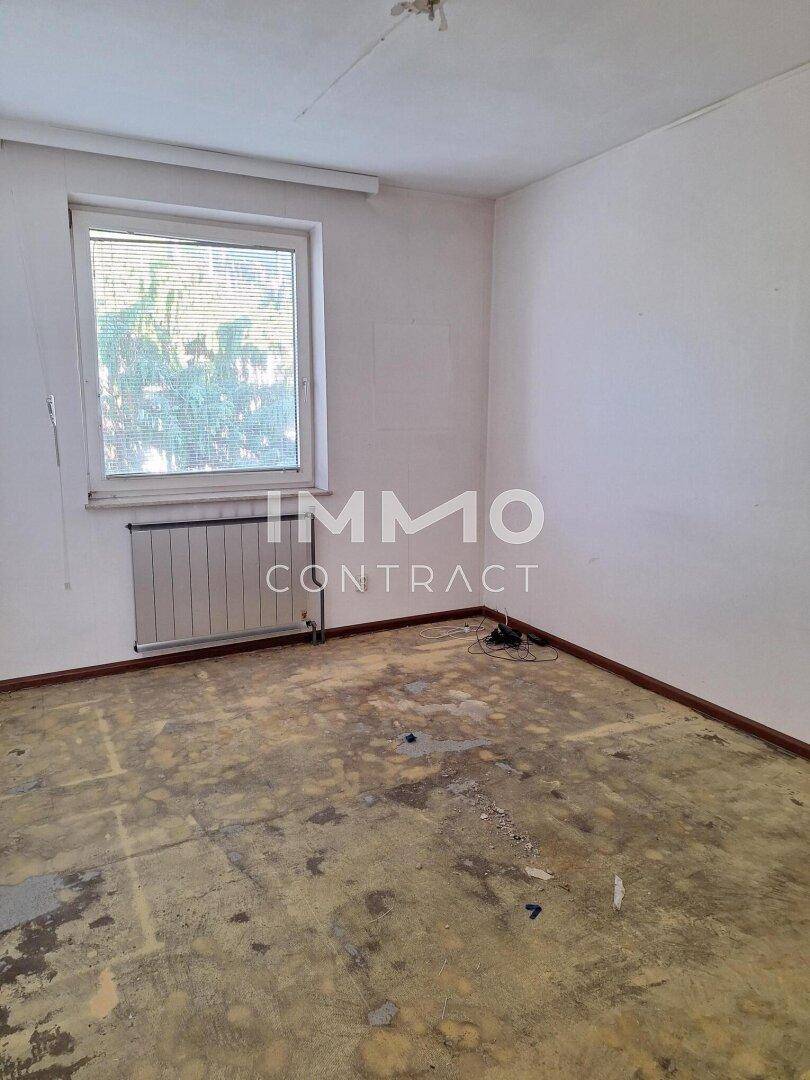 Leeres Schlafzimmer mit Fenster und Heizkörper, bietet eine gute Basis für die Neugestaltung.