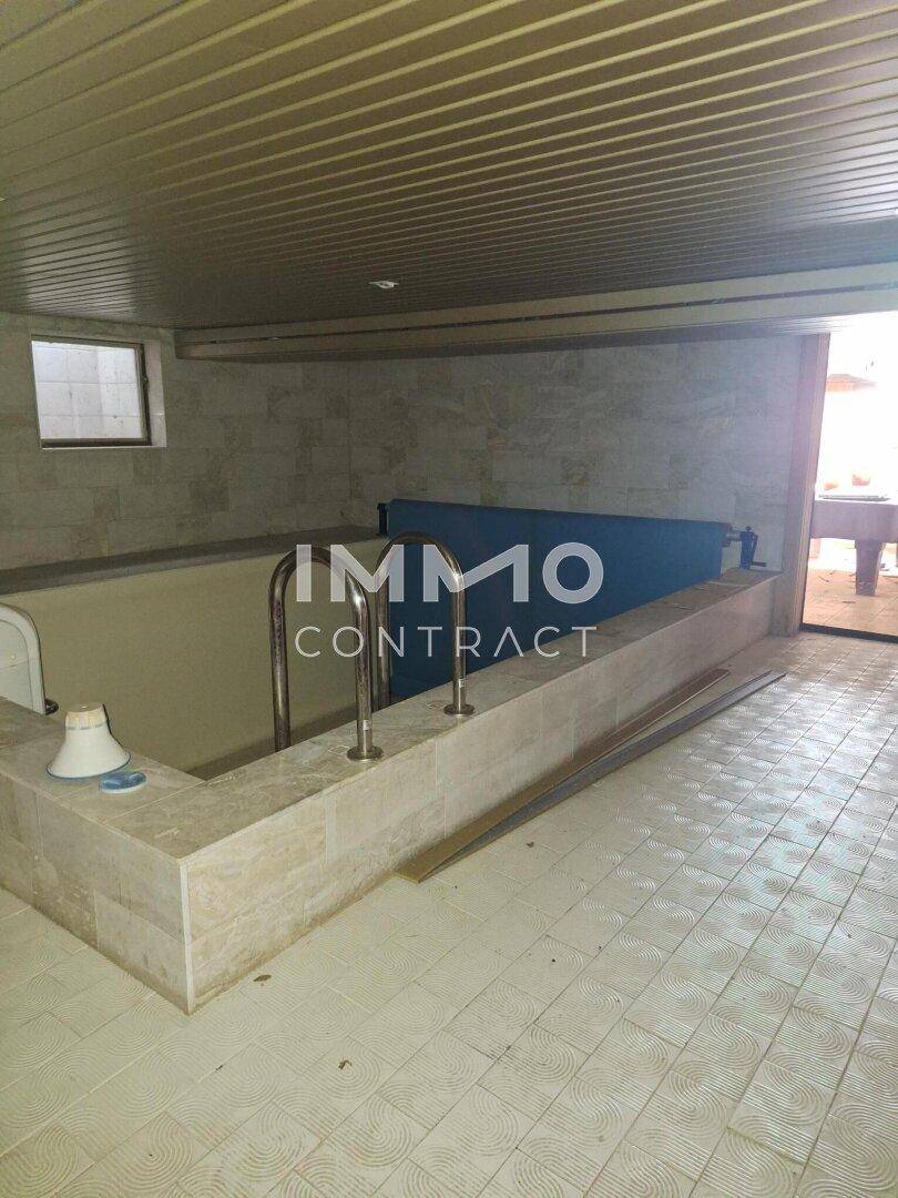 Innenpoolbereich mit gefliestem Boden und Zugang nach draußen, ideal für Entspannung und Sport.