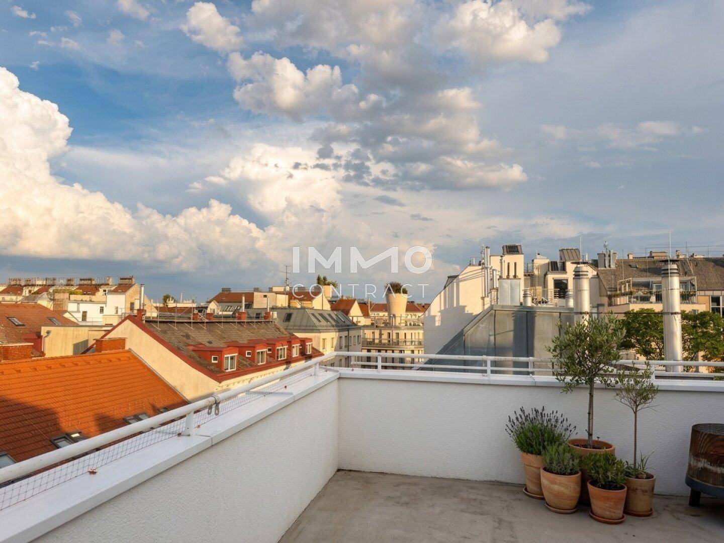 Offene Dachterrasse mit weitem Blick über die Dächer der Stadt unter einem bewölkten Himmel.