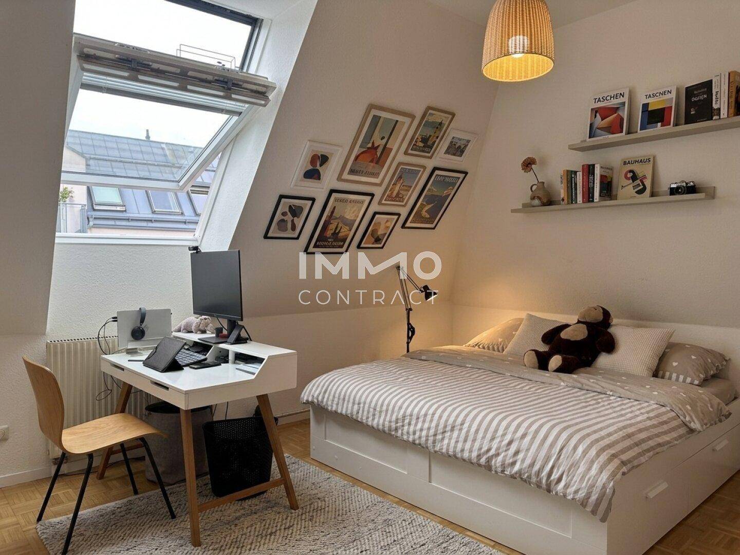 Helles Schlafzimmer mit Dachschrägen, Einzelbett, Schreibtisch und Blick aus dem Dachfenster.