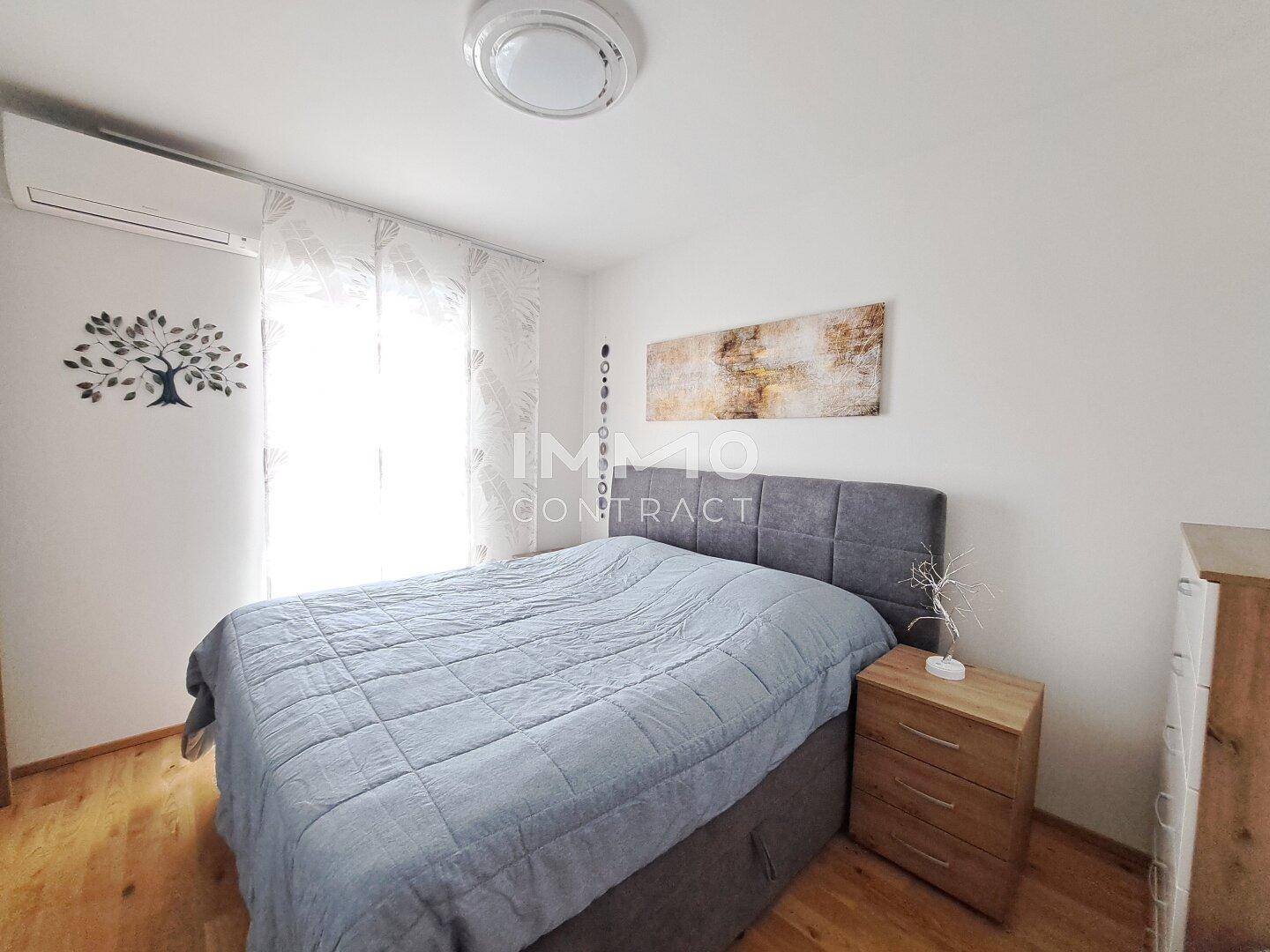 Schlafzimmer mit Doppelbett, Holzboden und Klimaanlage an der Wand.
