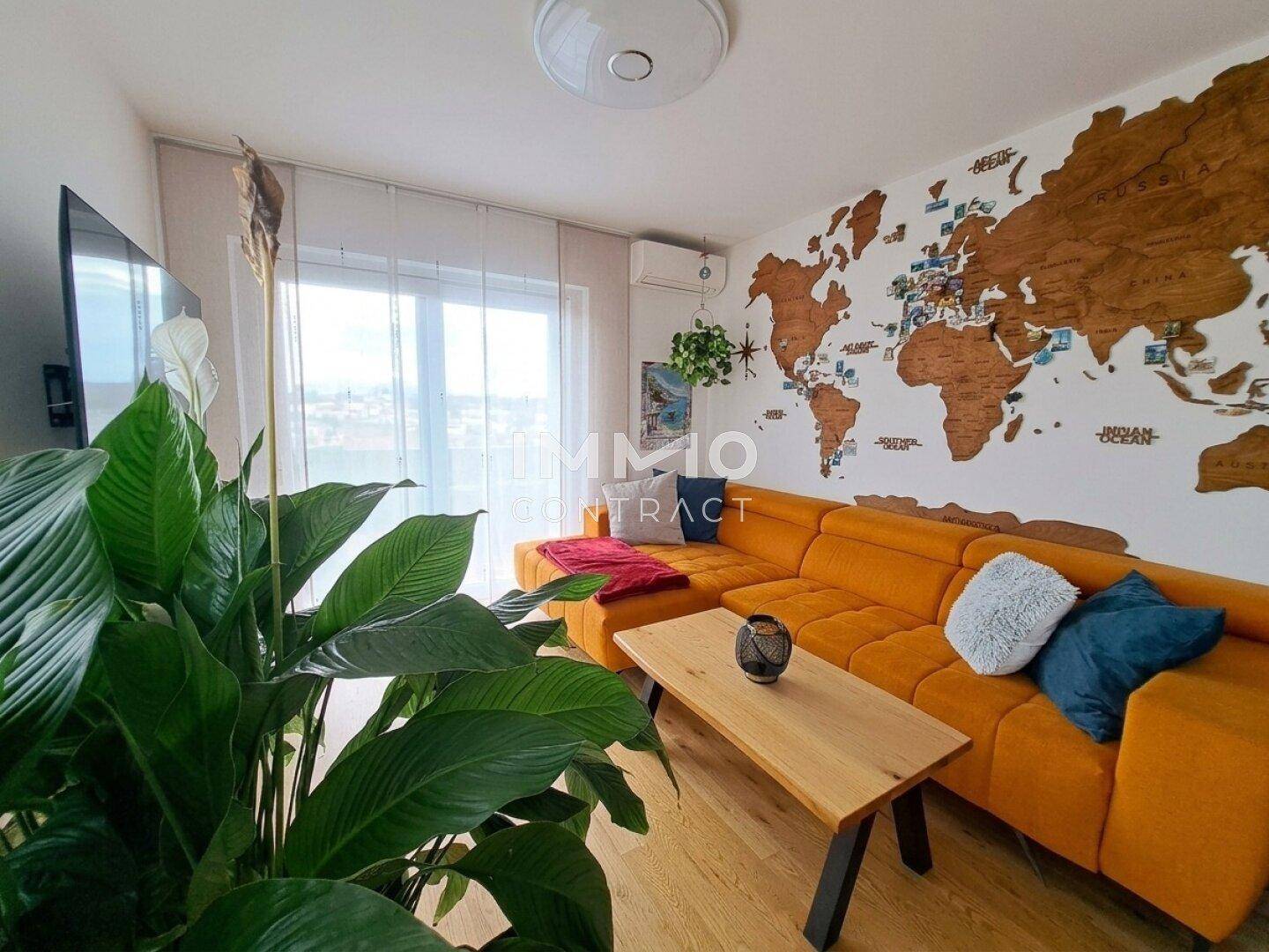 Gemütliches Wohnzimmer mit orangefarbenem Sofa, Holzboden und dekorativer Weltkarte an der Wand.