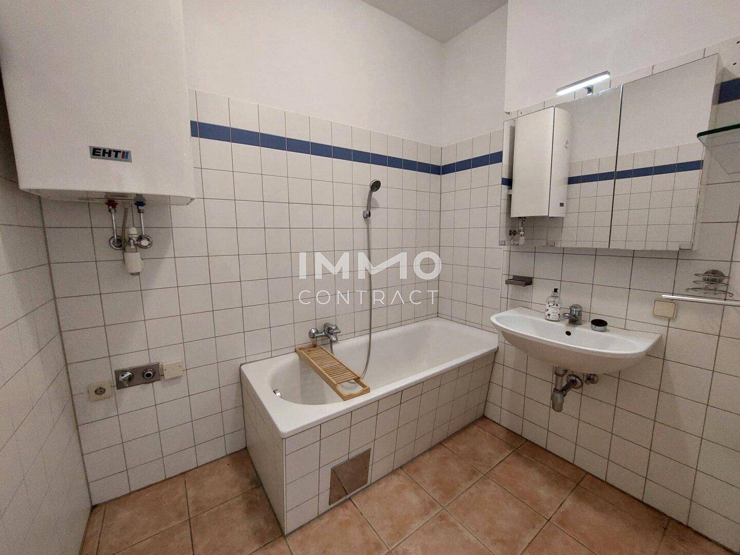 Badezimmer mit Badewanne, Waschbecken, Spiegelschrank und weißen Wandfliesen.