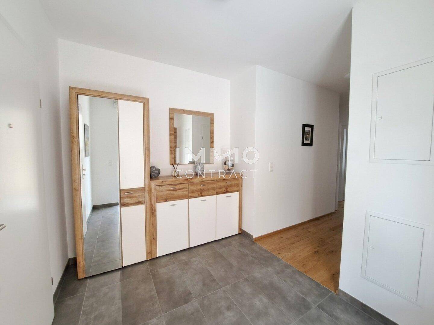 Eingangsbereich mit Fliesenboden, Garderobe und Spiegel.