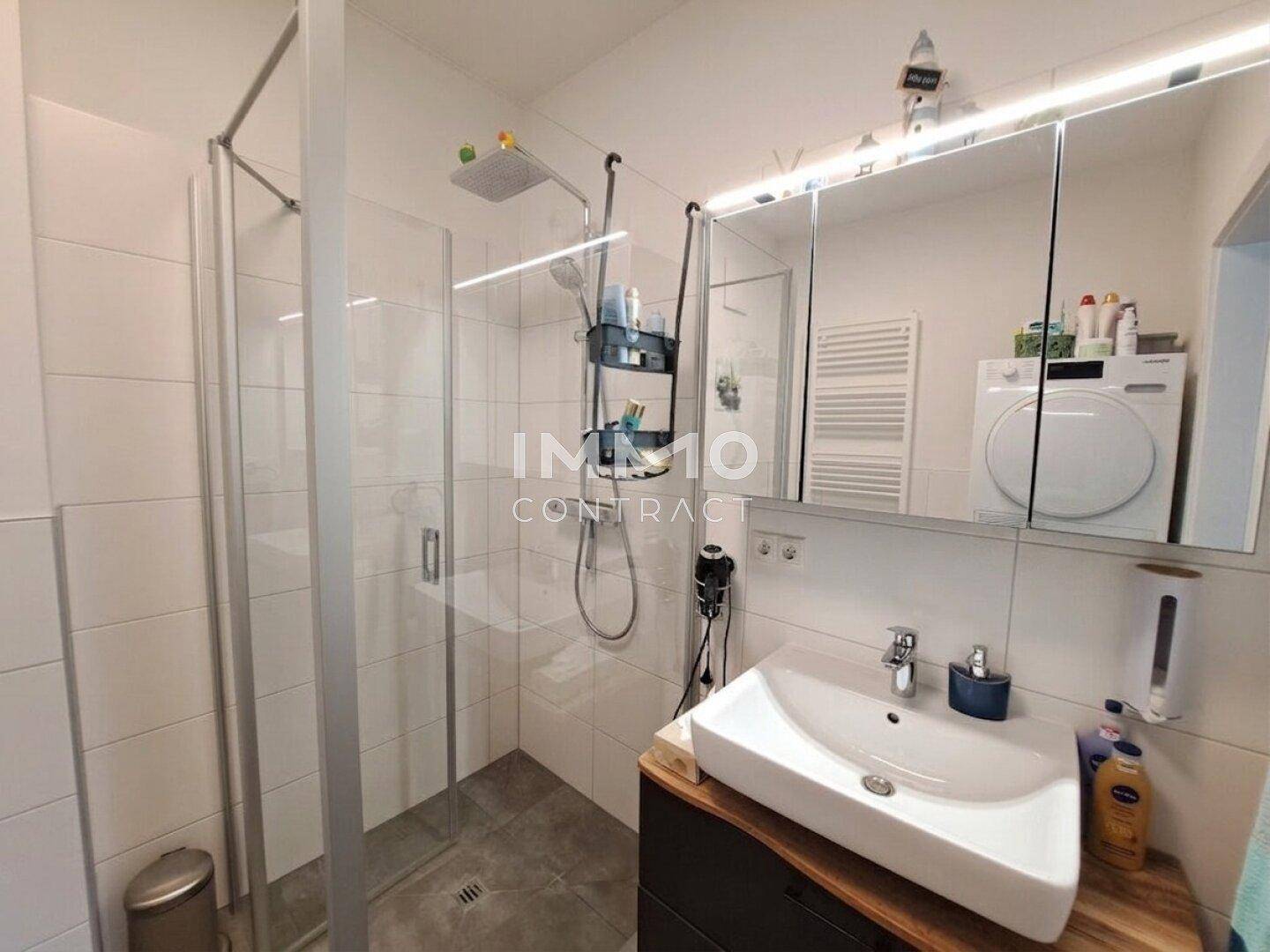 Modernes Badezimmer mit Duschkabine, Waschbecken und Spiegelschrank.