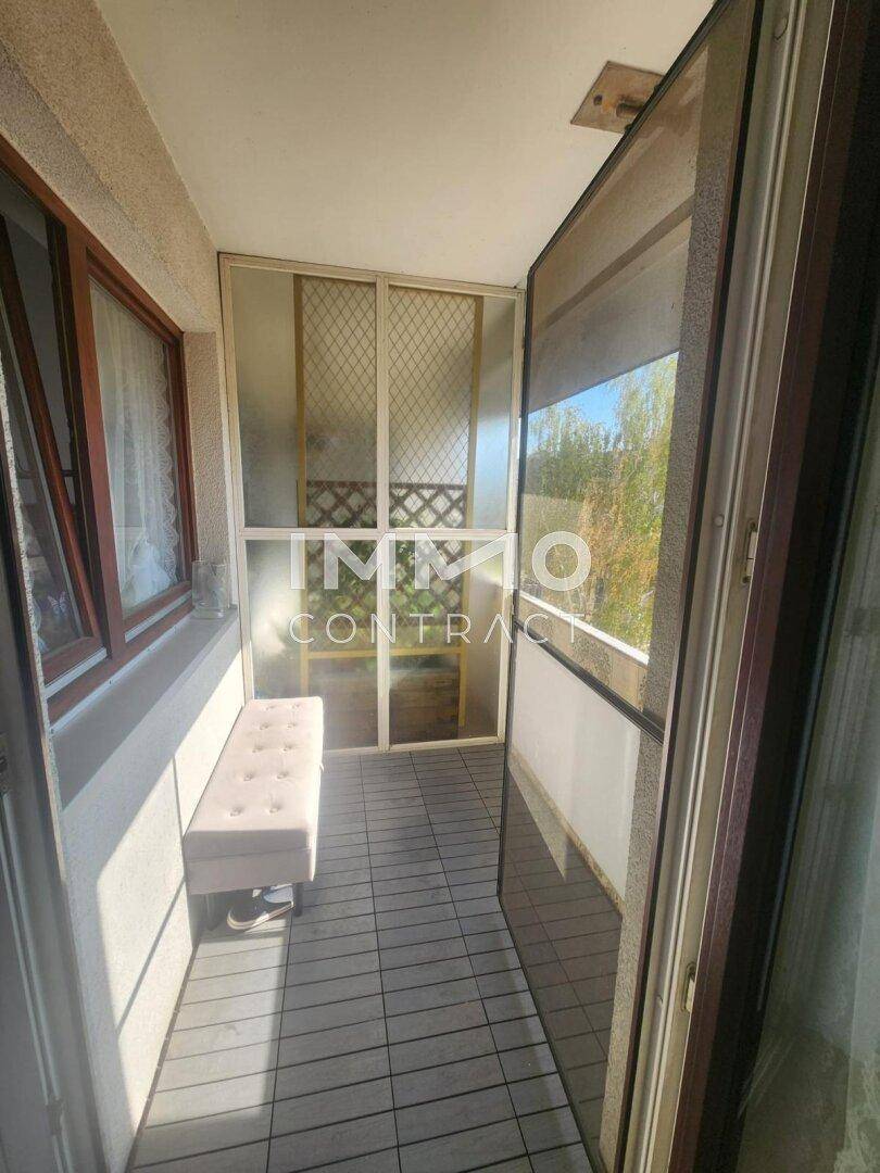 Überdachter Balkon mit Sitzbank und Fliesenboden, ideal zum Entspannen im Freien.