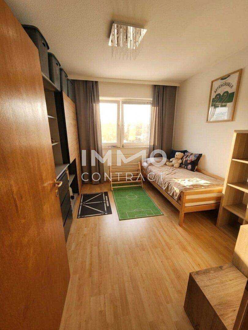 Kinderzimmer mit Holzboden, Einzelbett und praktischer Schrankwand.