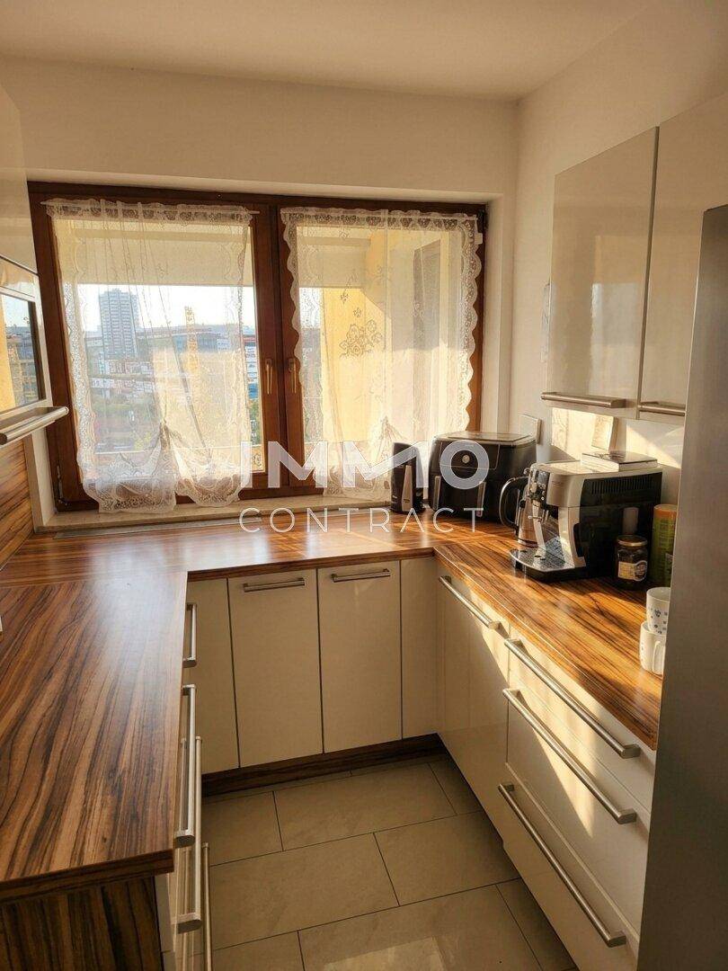 Moderne Küche mit hellen Schränken, Holzoptik-Arbeitsplatten und Fliesenboden.