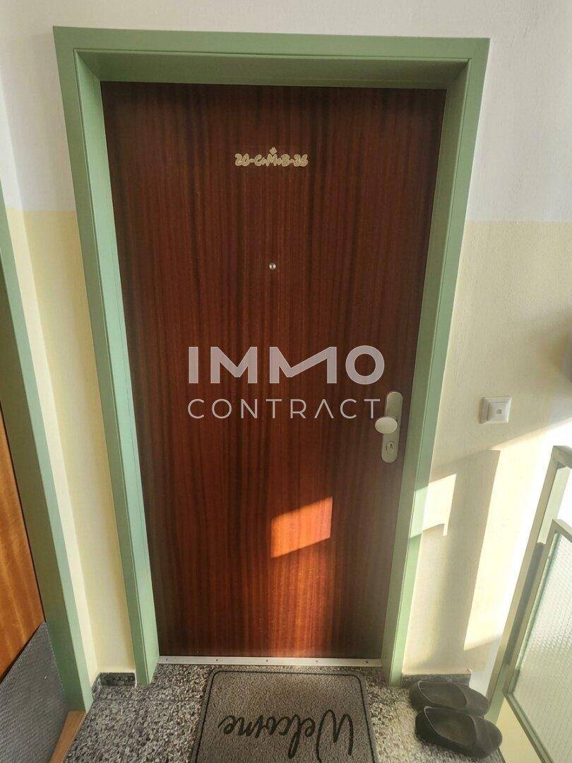 Eingangstür einer Wohnung mit Holzoptik und grünem Rahmen im Flur.