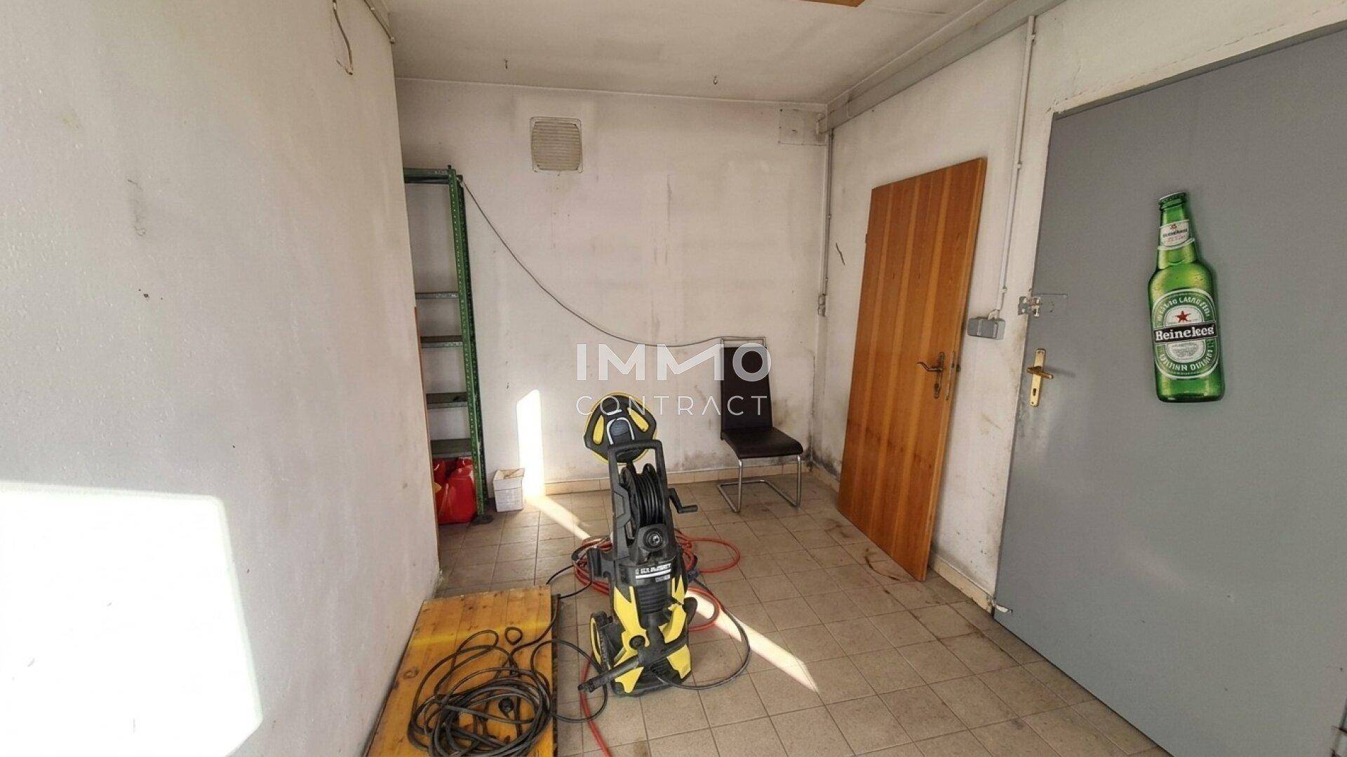 Geräumiger Abstellraum oder Werkstatt mit Fliesenboden und verschiedenen Geräten.
