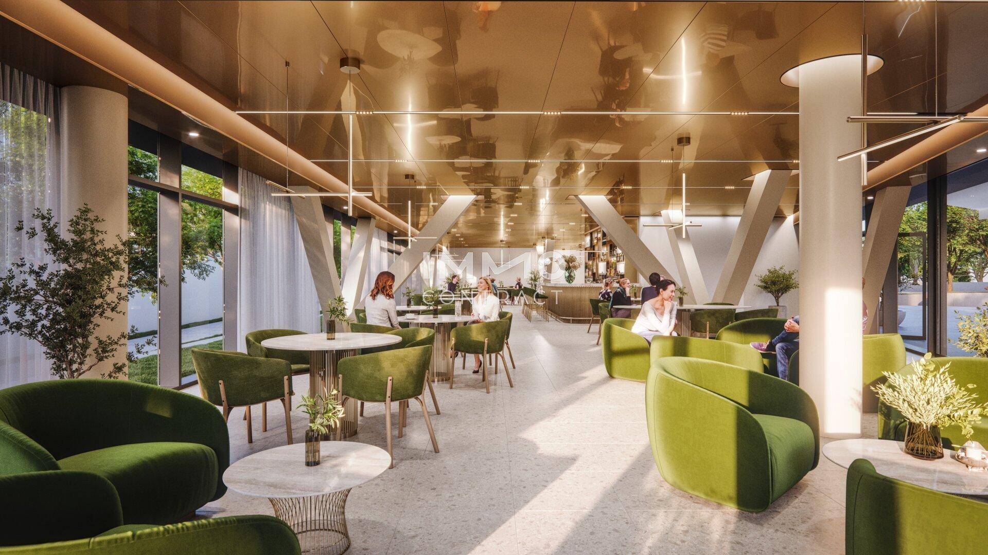 Moderner Loungebereich eines Restaurants mit bequemen grünen Sesseln und Tischen unter einer goldenen Decke.