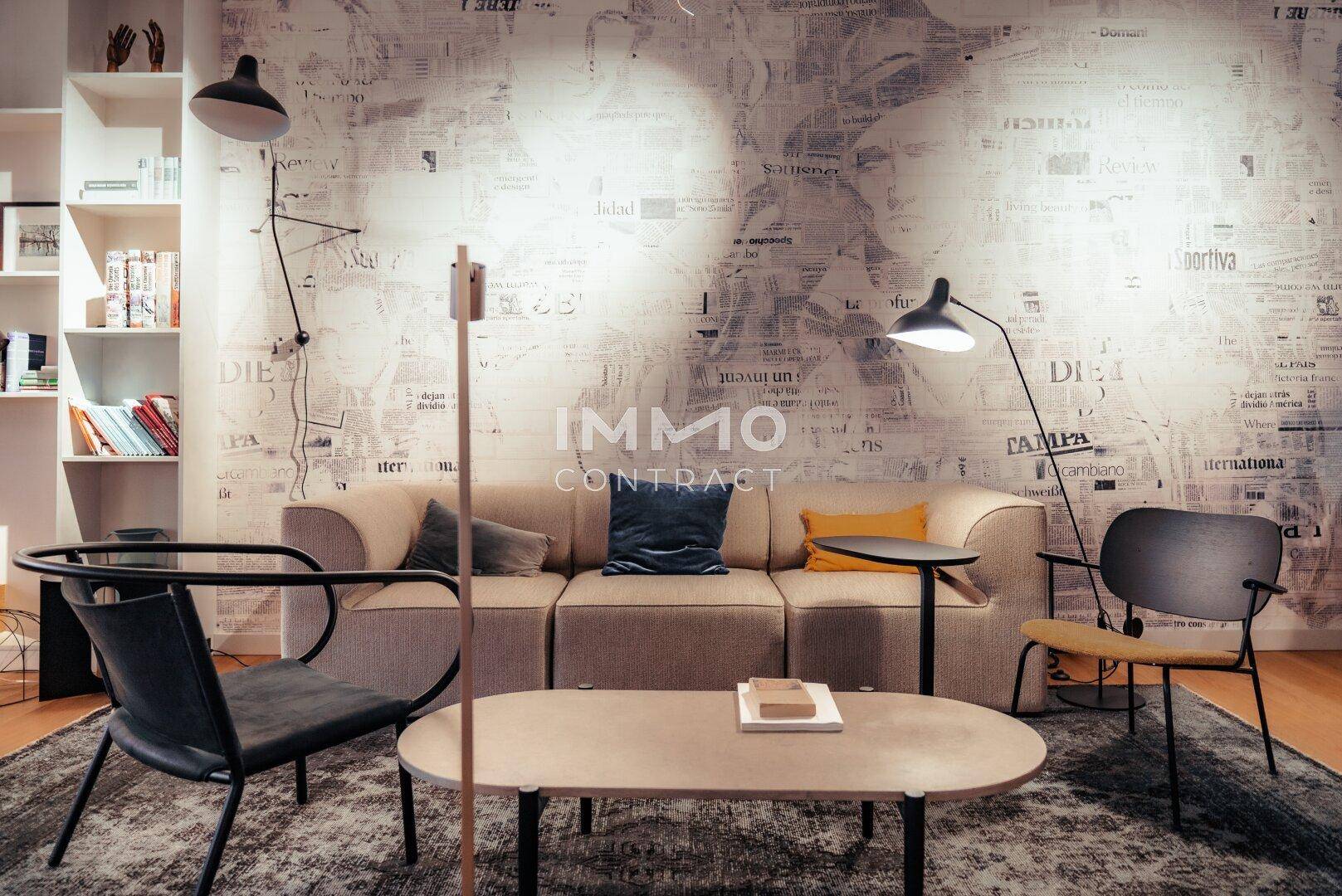 Gemütlicher Loungebereich mit Sofa, Couchtisch und auffälliger Tapete, ergänzt durch moderne Stehlampen.