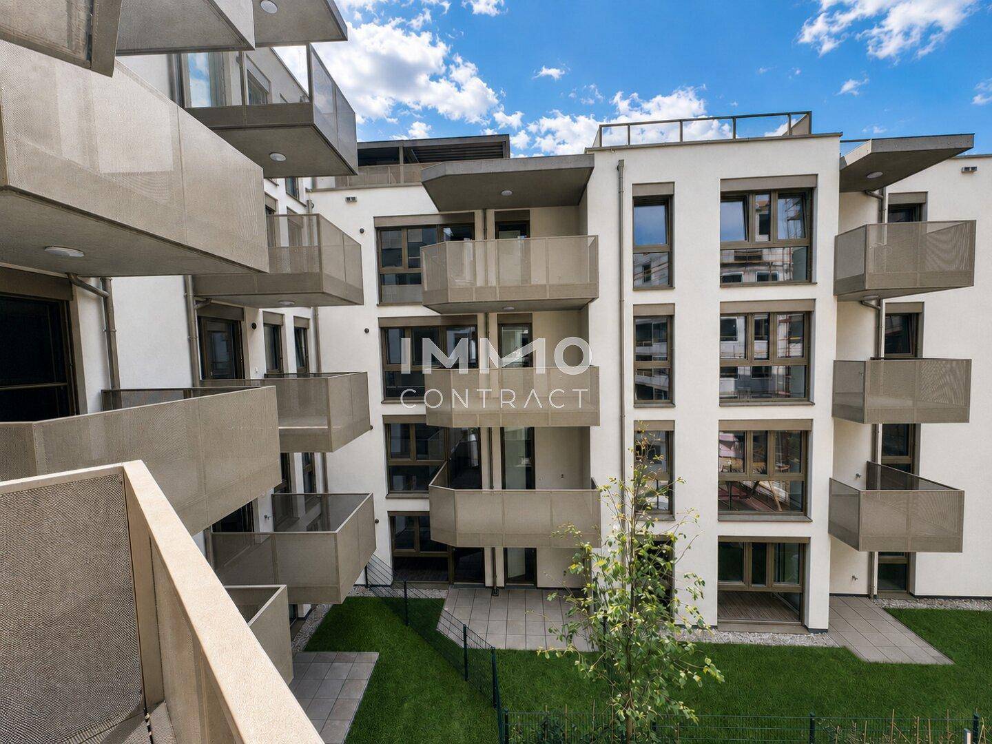 Moderne Wohnanlage mit zahlreichen Balkonen und gepflegter Grünfläche im Innenhof.