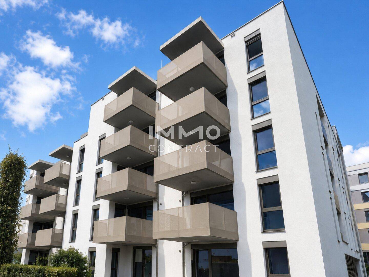 Attraktive Neubaufassade mit gestaffelten Balkonen und großen Fenstern unter blauem Himmel.