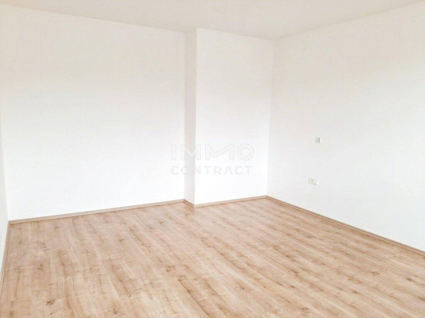 Heller Raum mit sauberem Holzboden und frisch gestrichenen weißen Wänden.