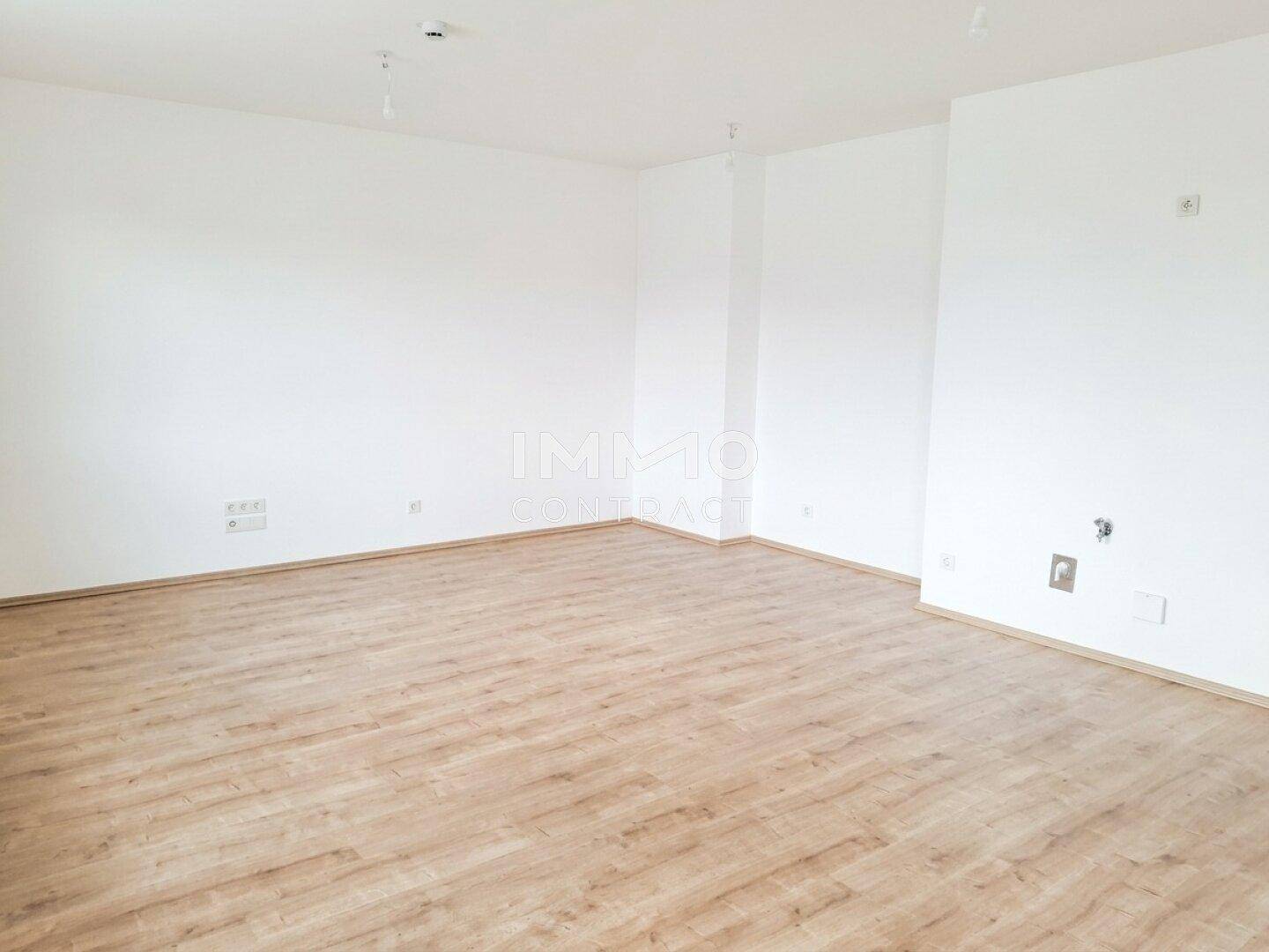 Geräumiges, leeres Zimmer mit hellem Holzboden und weißen Wänden.