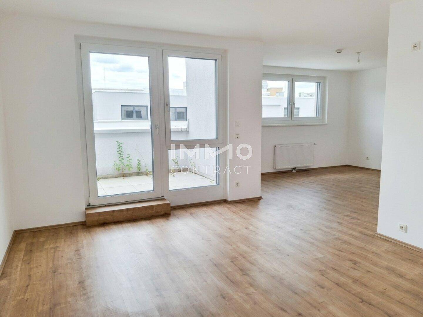 Geräumiger Wohnbereich mit großen Fenstern und Terrassenzugang, der viel Tageslicht bietet.