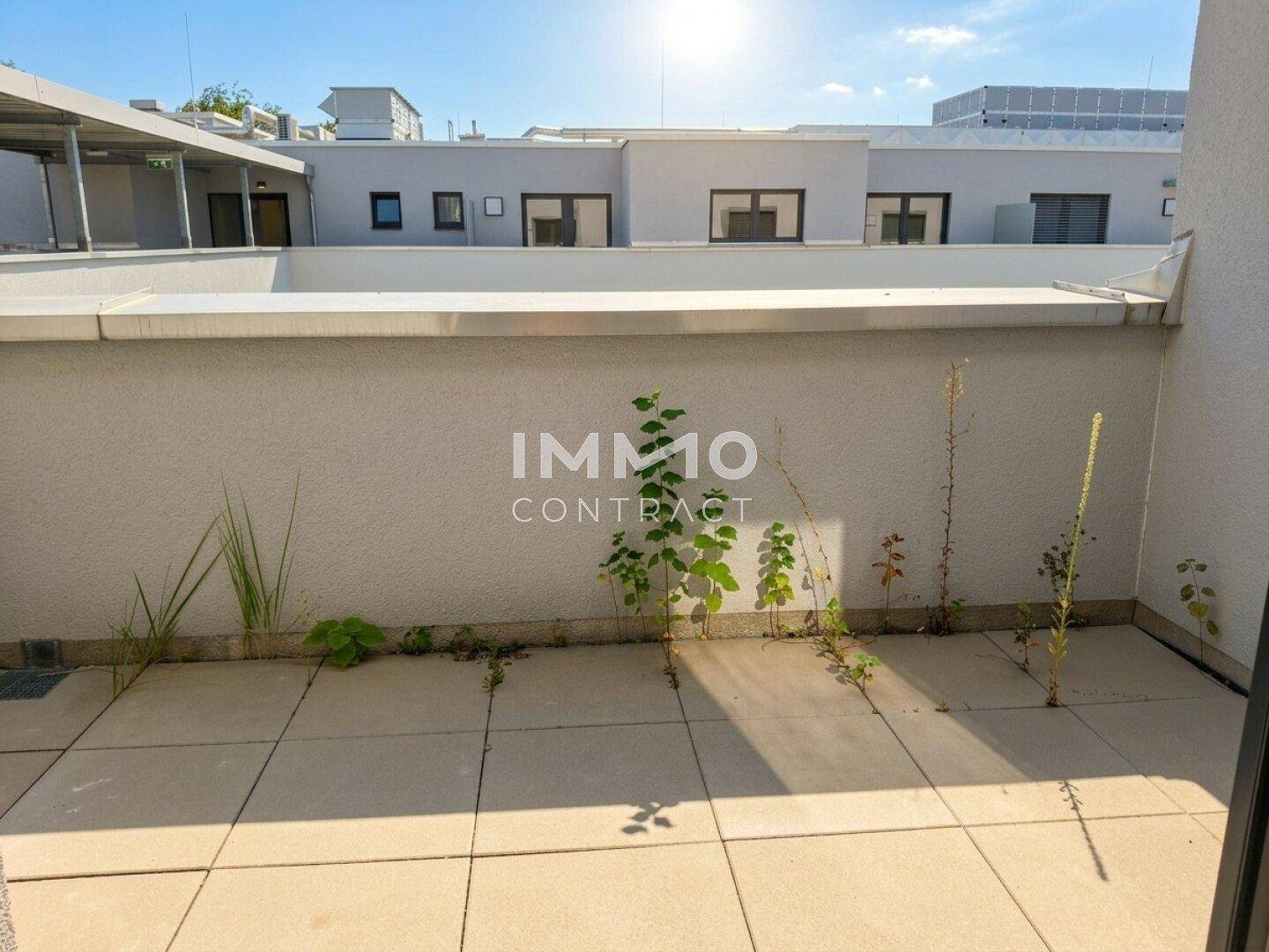 Unmöblierte Terrasse mit Fliesenboden und Blick auf die umliegenden Gebäude.