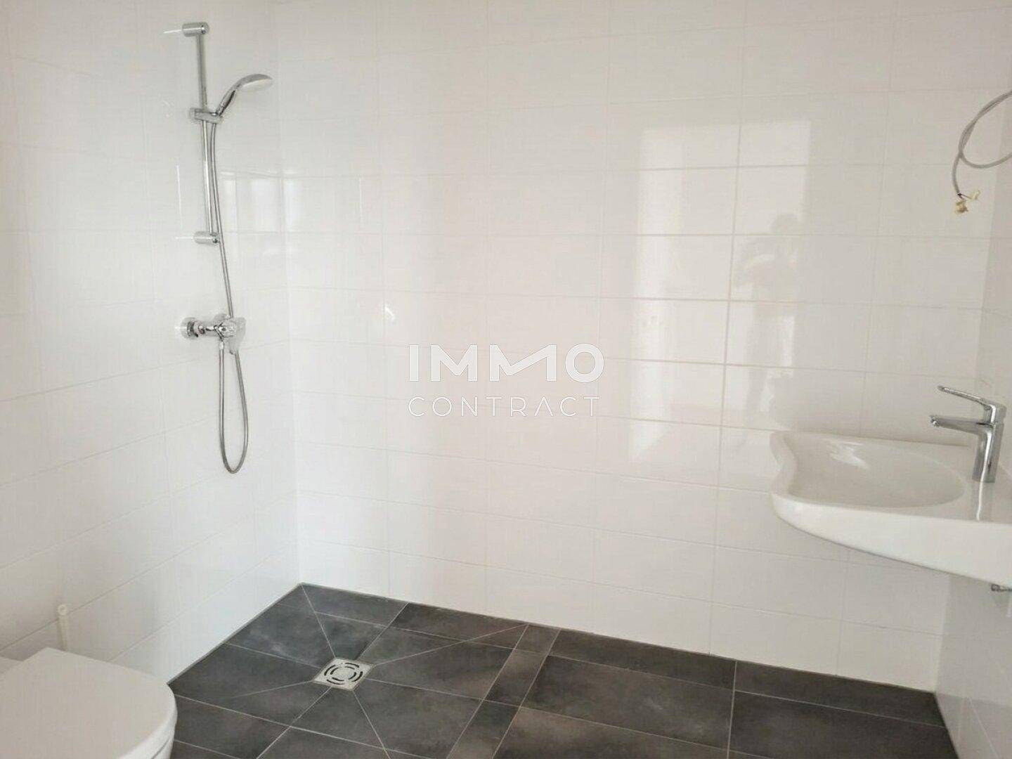 Modernes Badezimmer mit weißen Fliesen, Dusche und Waschbecken.