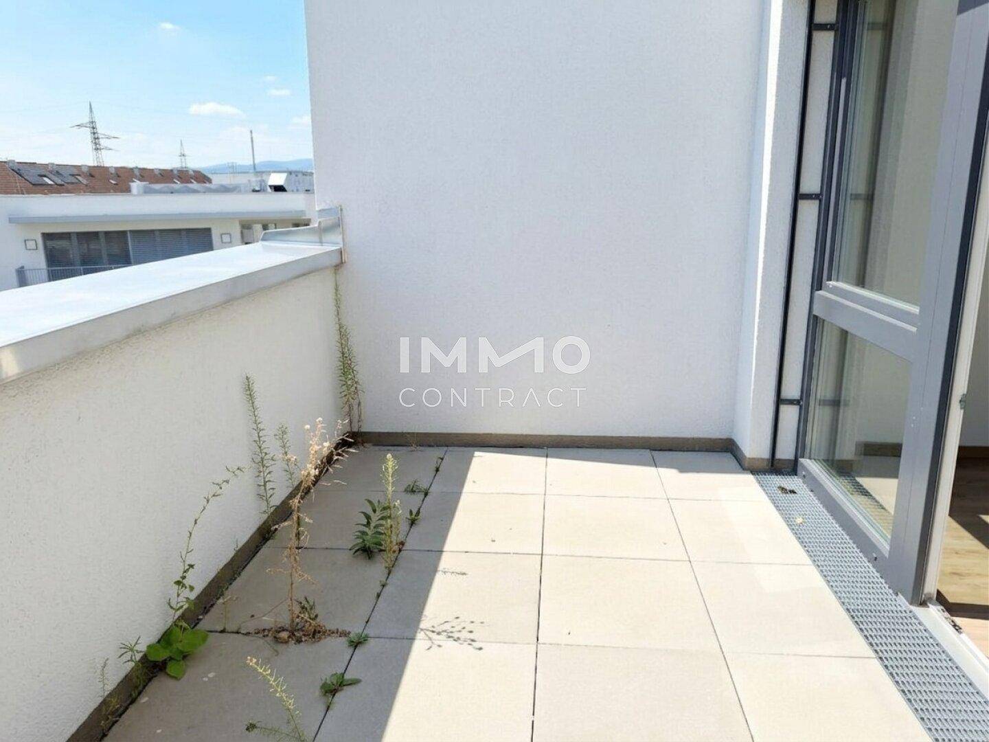Heller Balkon mit Fliesenboden und Zugang zum Innenraum.