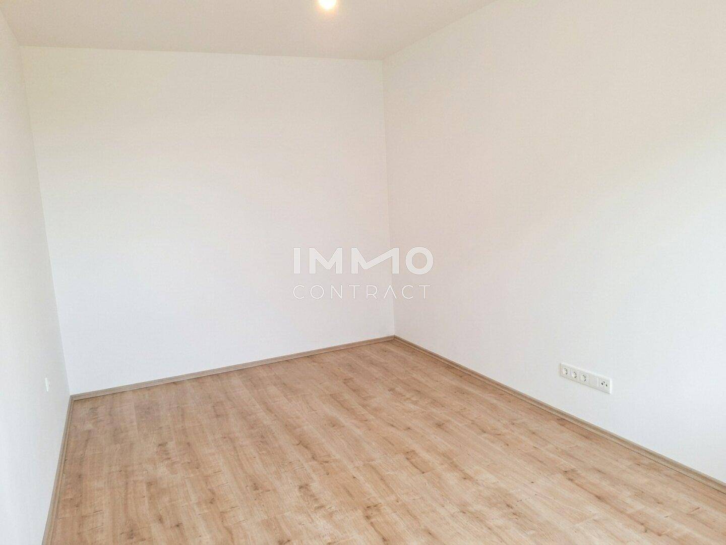 Ruhiges Schlafzimmer mit hellem Laminatboden und weißen Wänden, ideal für individuelle Einrichtung.