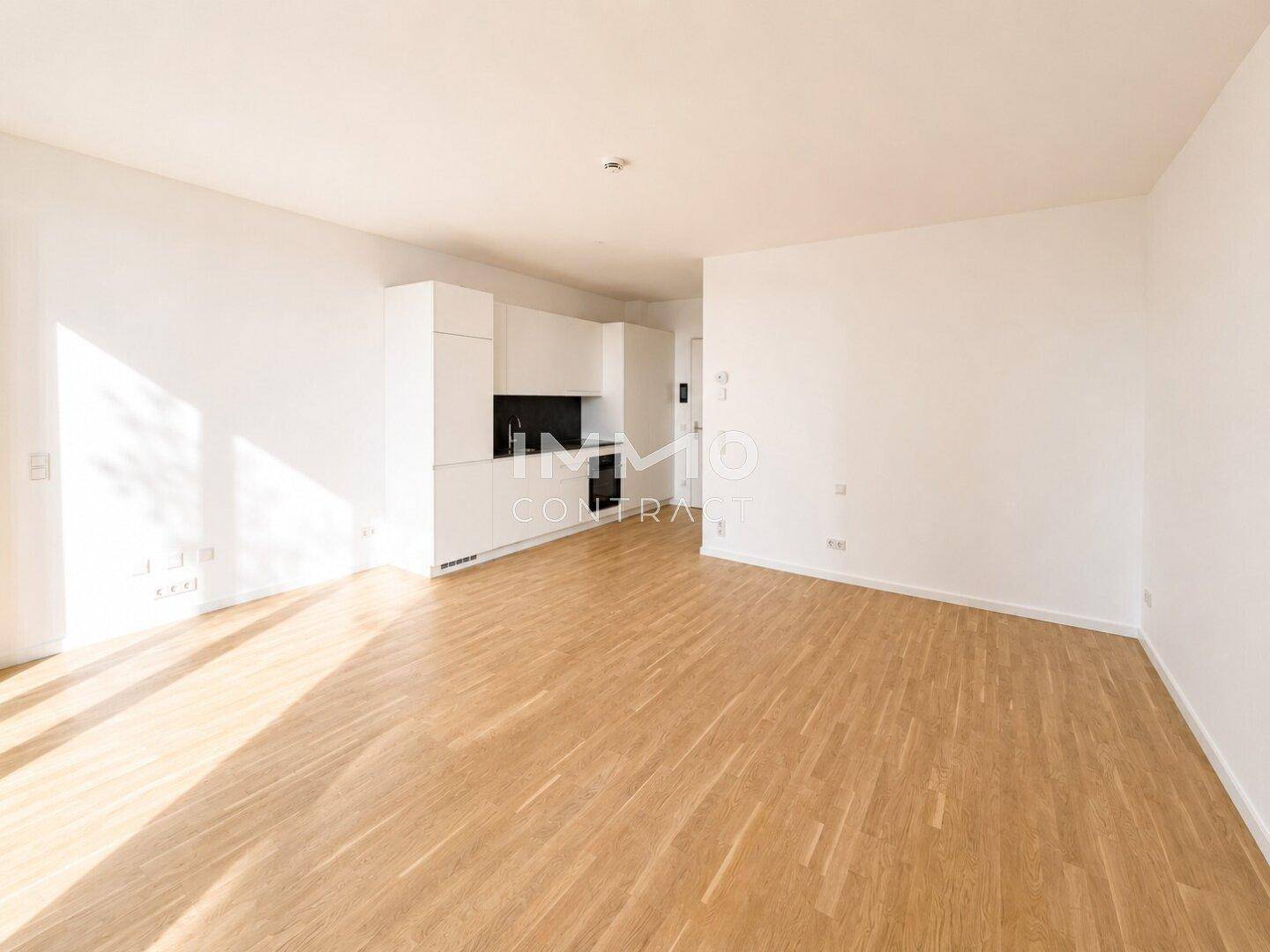 Heller Wohnbereich mit integrierter Küchenzeile und modernem Holzboden, ideal für Singles oder Paare.