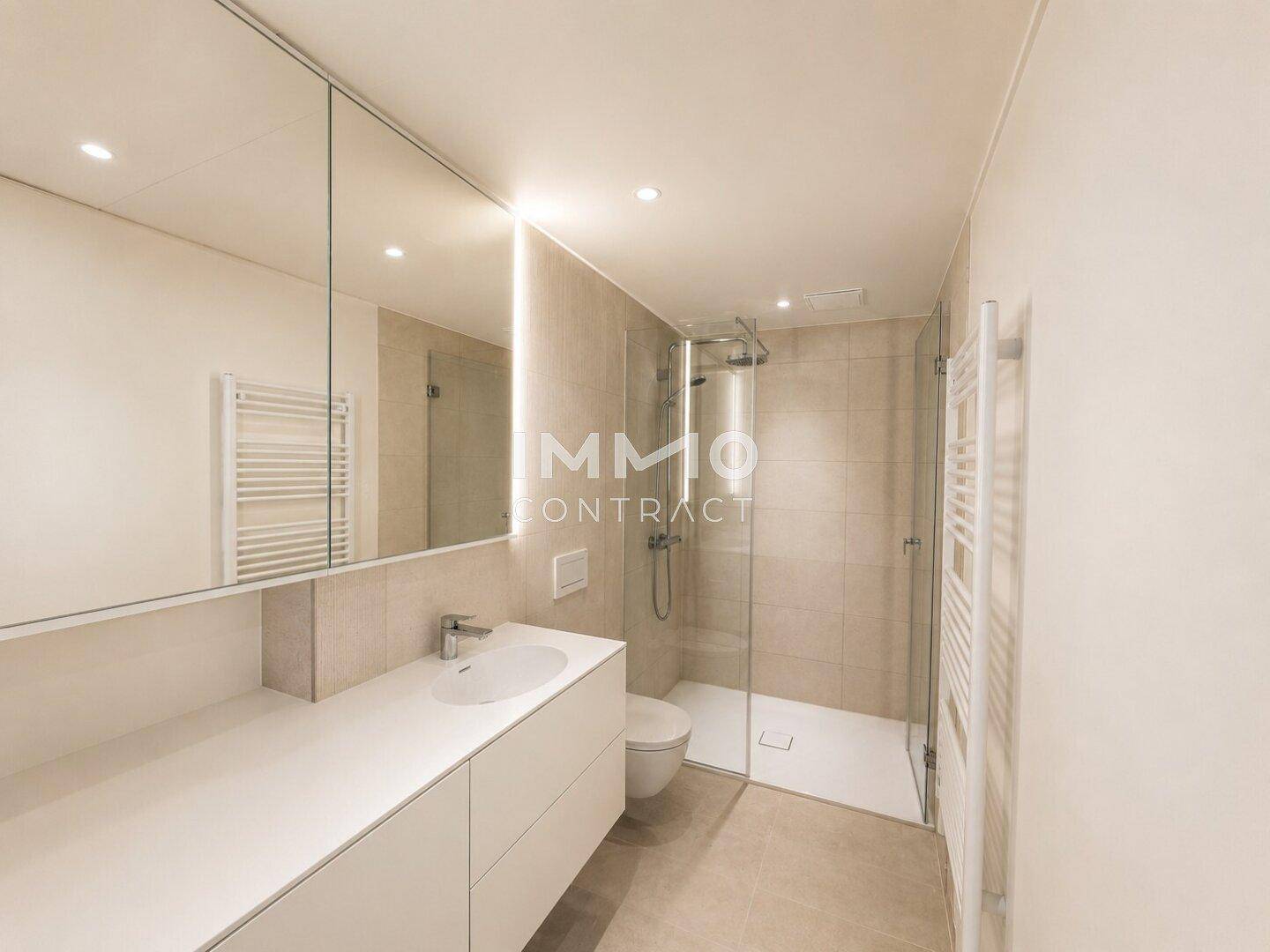 Modernes Badezimmer mit ebenerdiger Dusche, elegantem Waschtisch und beheiztem Handtuchhalter.