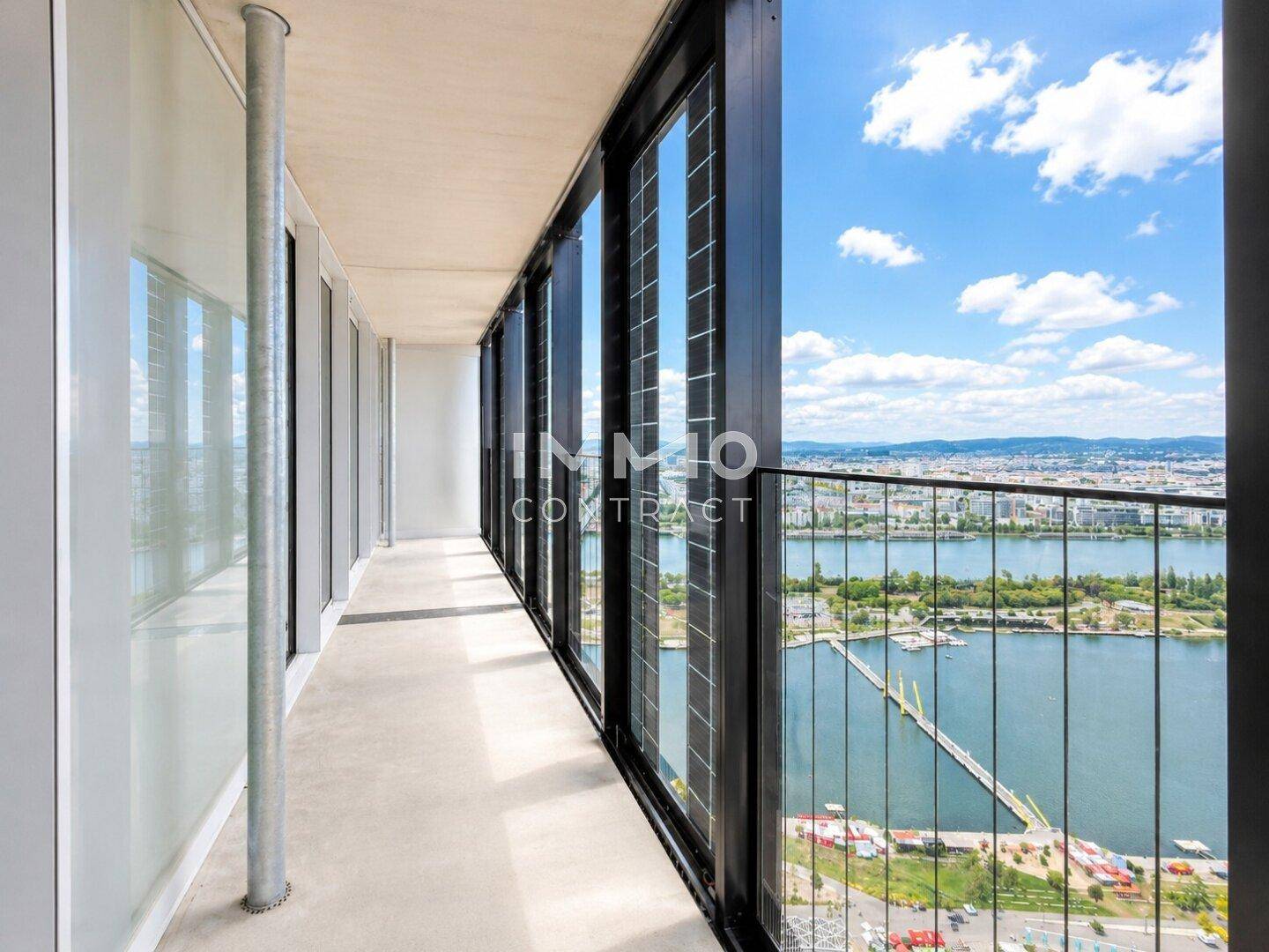 Langer Balkon mit Glasbrüstung und Panoramablick auf den Fluss und die Stadt.