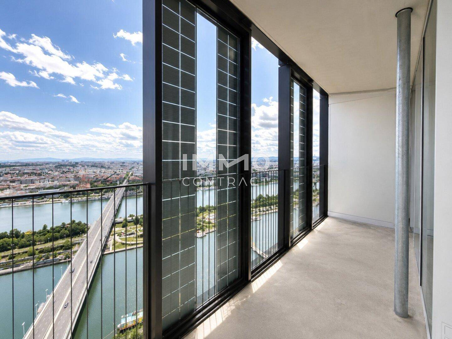 Geräumiger Balkon mit Glasgeländer und beeindruckendem Blick auf den Fluss und die Stadtlandschaft.