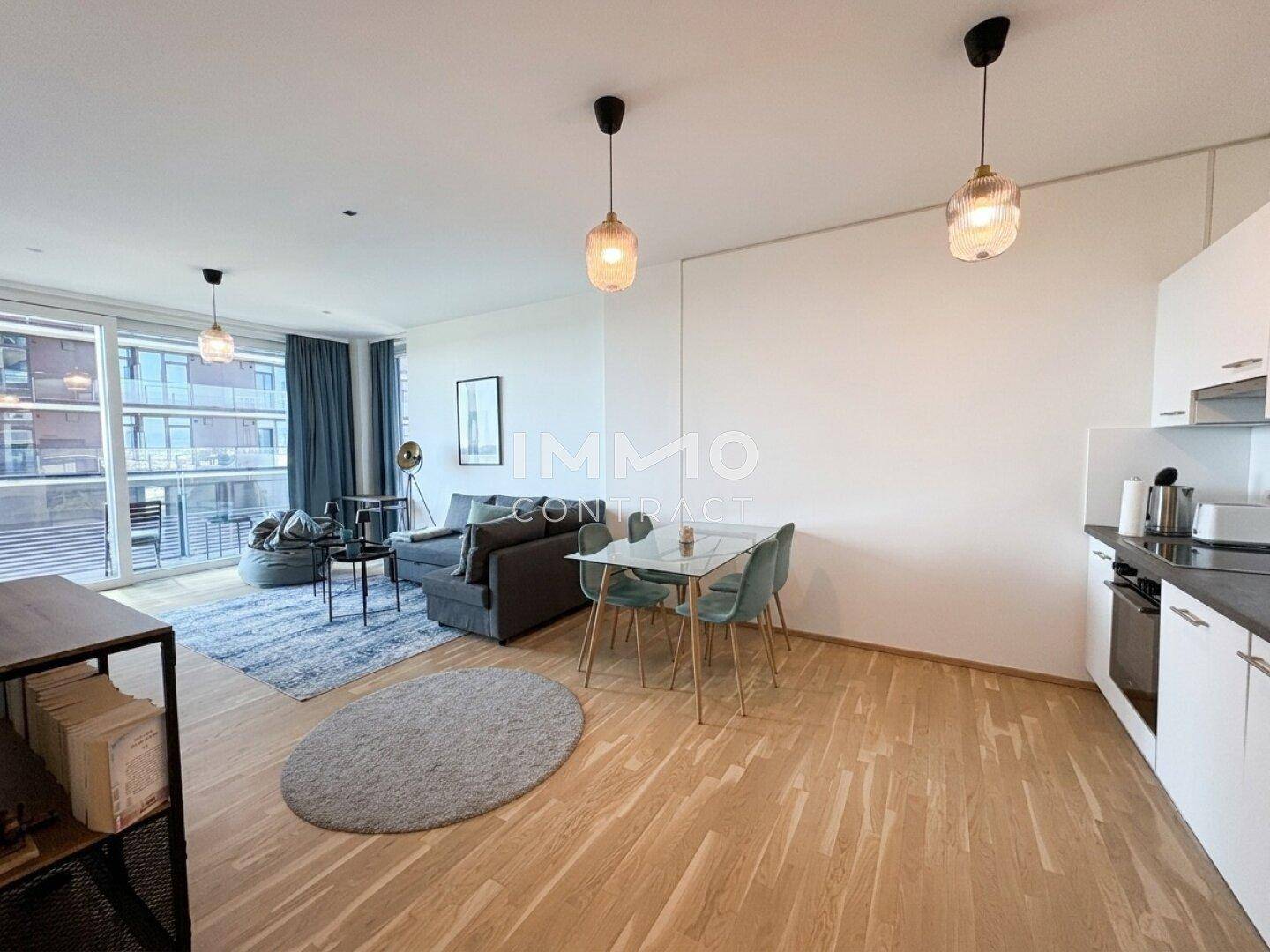 Offener Wohn- und Essbereich mit integrierter Küche, Parkettboden und Zugang zum Balkon.