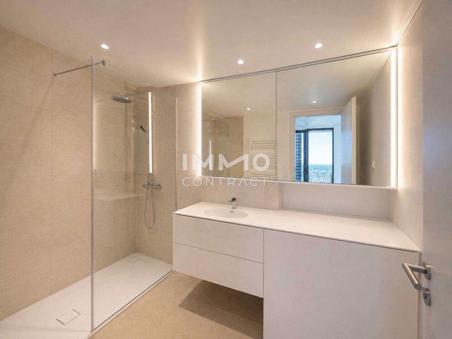 Modernes Badezimmer mit begehbarer Dusche, großem Waschtisch und beleuchtetem Spiegelschrank.