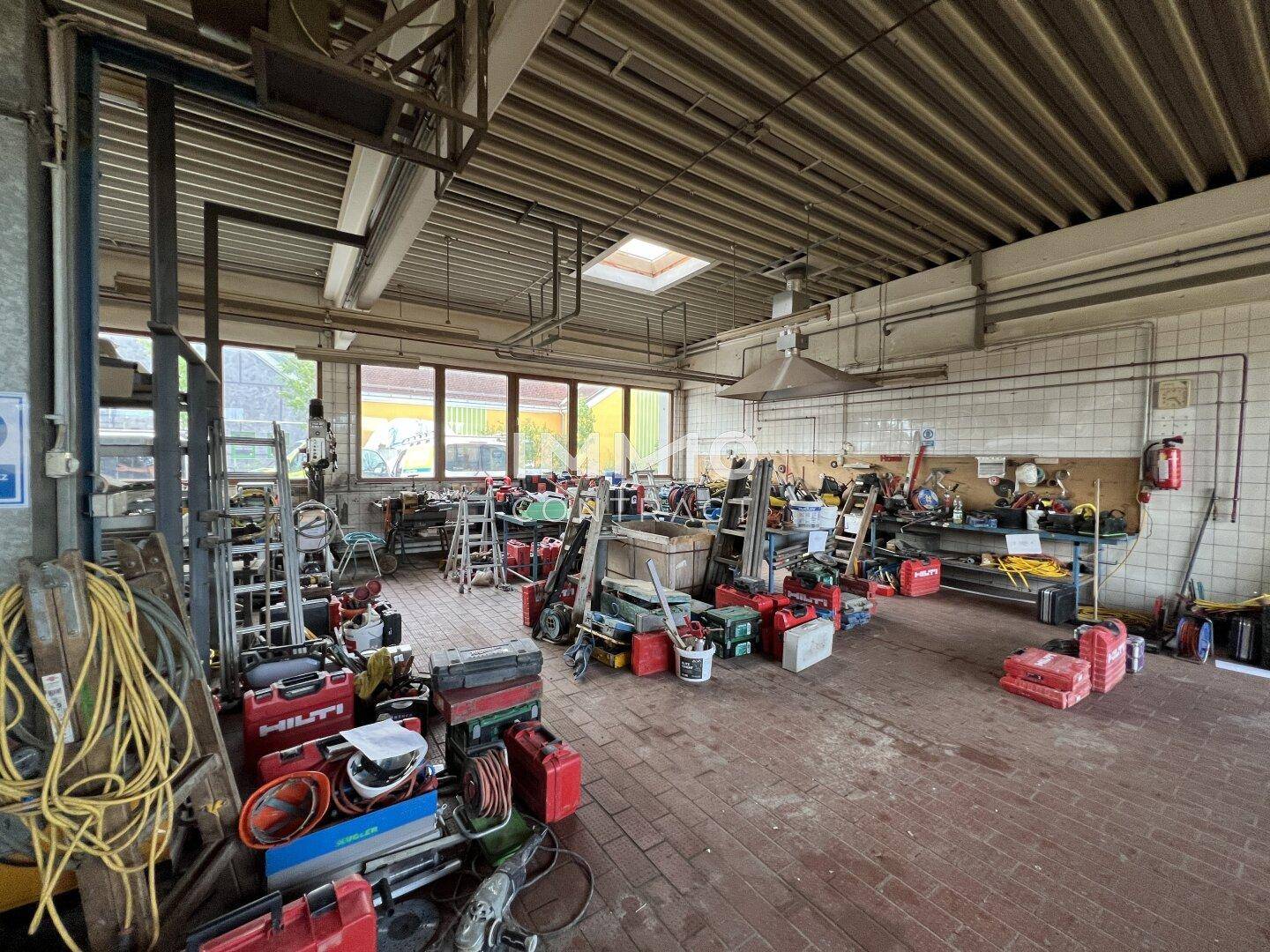 Geräumige Werkstatt mit vielen Werkzeugen, Arbeitsflächen und einem Oberlicht, ideal für handwerkliche Tätigkeiten.