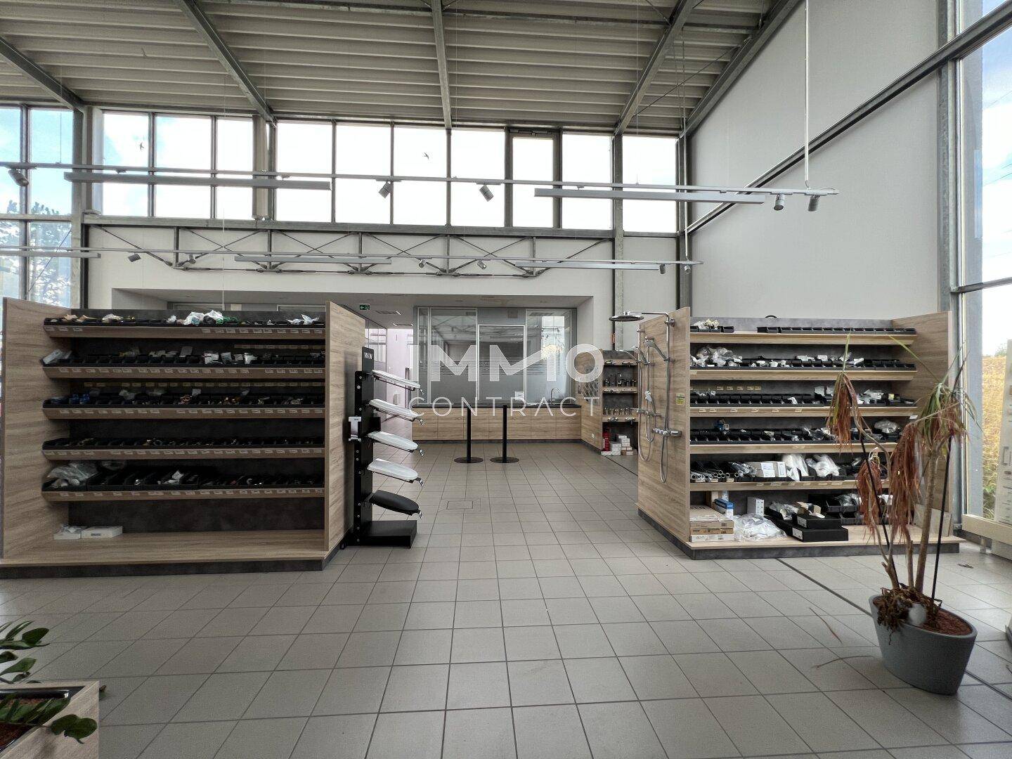 Offener Verkaufsraum mit hohen Decken, Fliesenboden und Regalen für die Produktpräsentation, hell und geräumig.